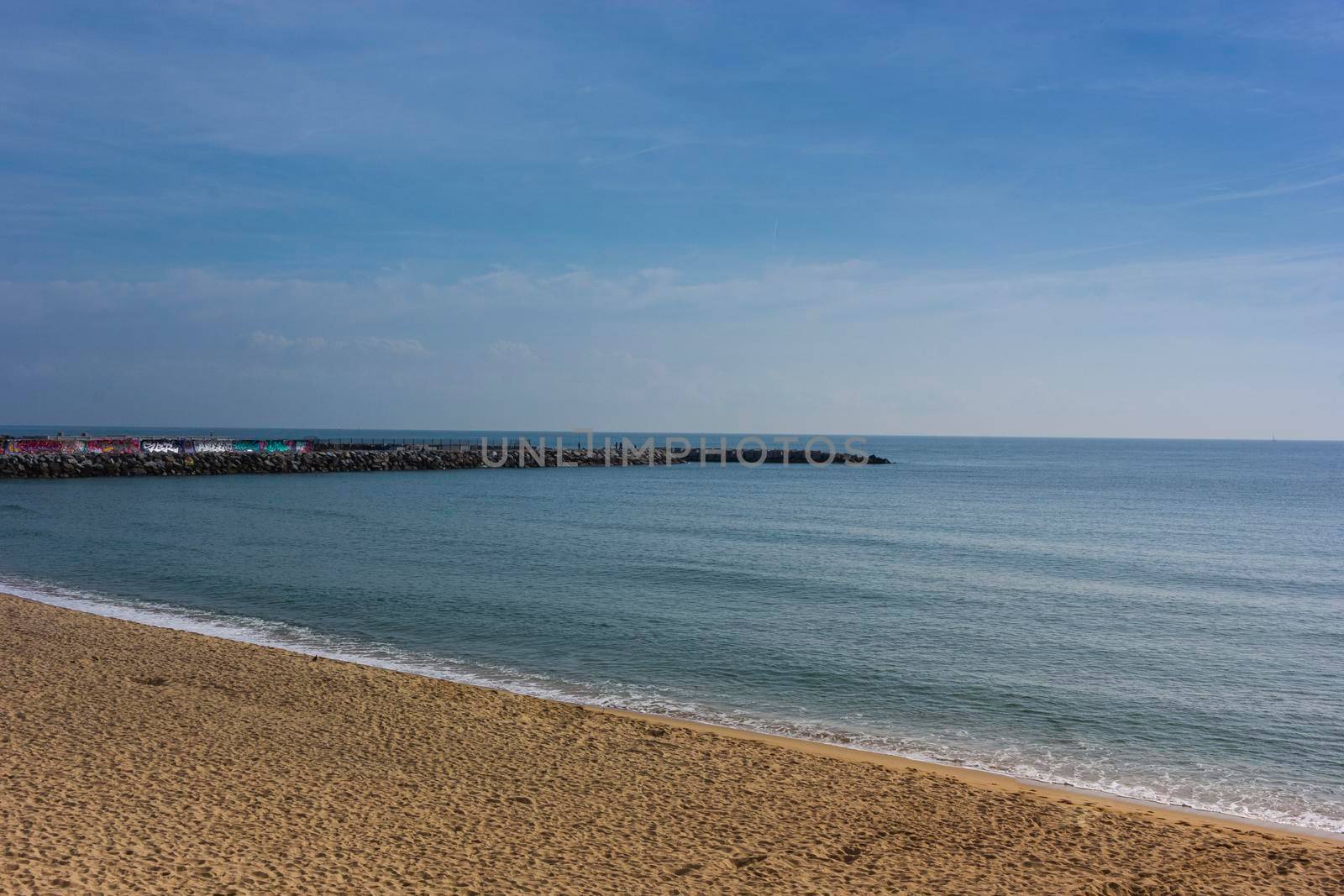 Barcelona beach in winter, with a calm sea and a cloudy blue sky