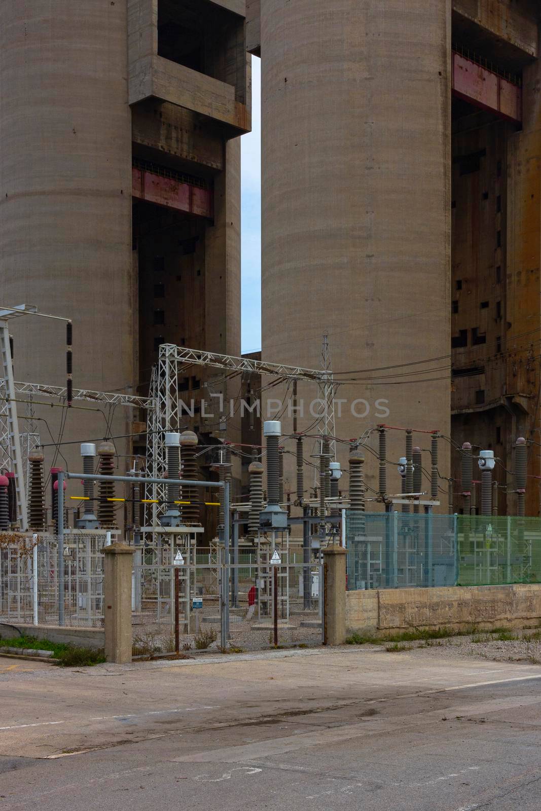Old disused thermal power plant for the production of electricity in Barcelona behind a metal fence by loopneo
