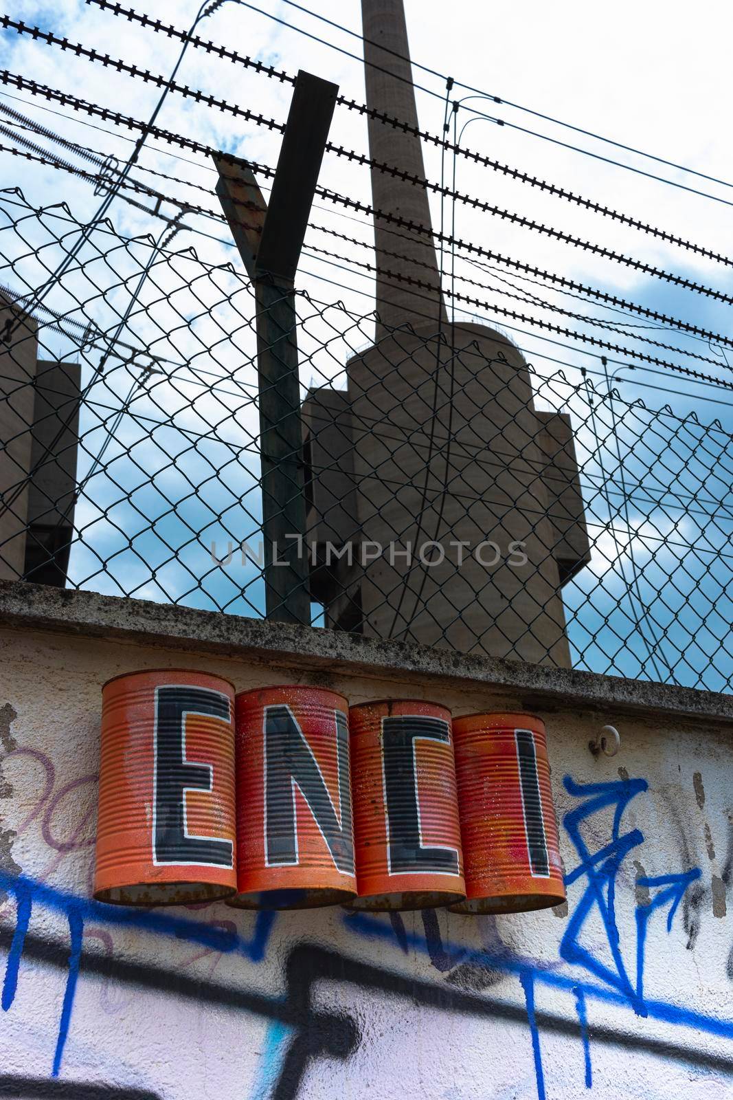 Urban art on the wall of an old disused thermal power plant for the production of electricity in Barcelona behind a metal fence
