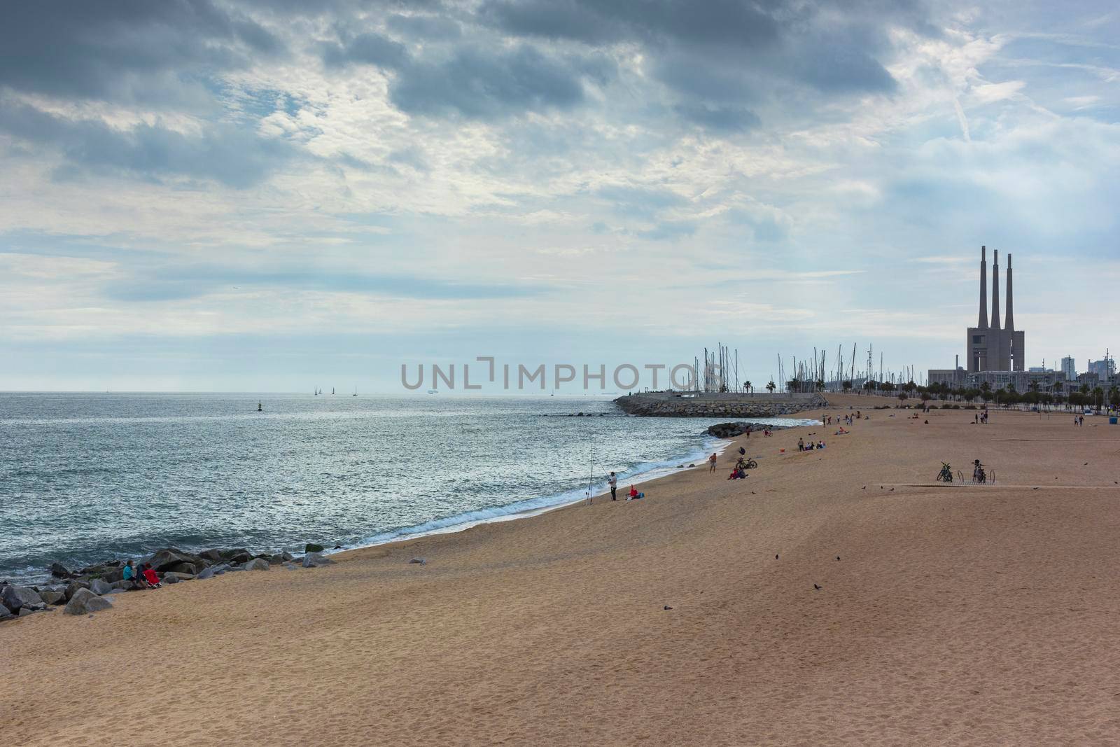 Barcelona beach in winter, with a calm sea and a cloudy blue sky