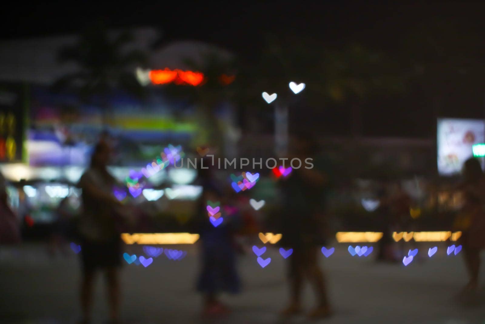 blur people selfie with heart shape love valentine colorful object on night light of shopping mall