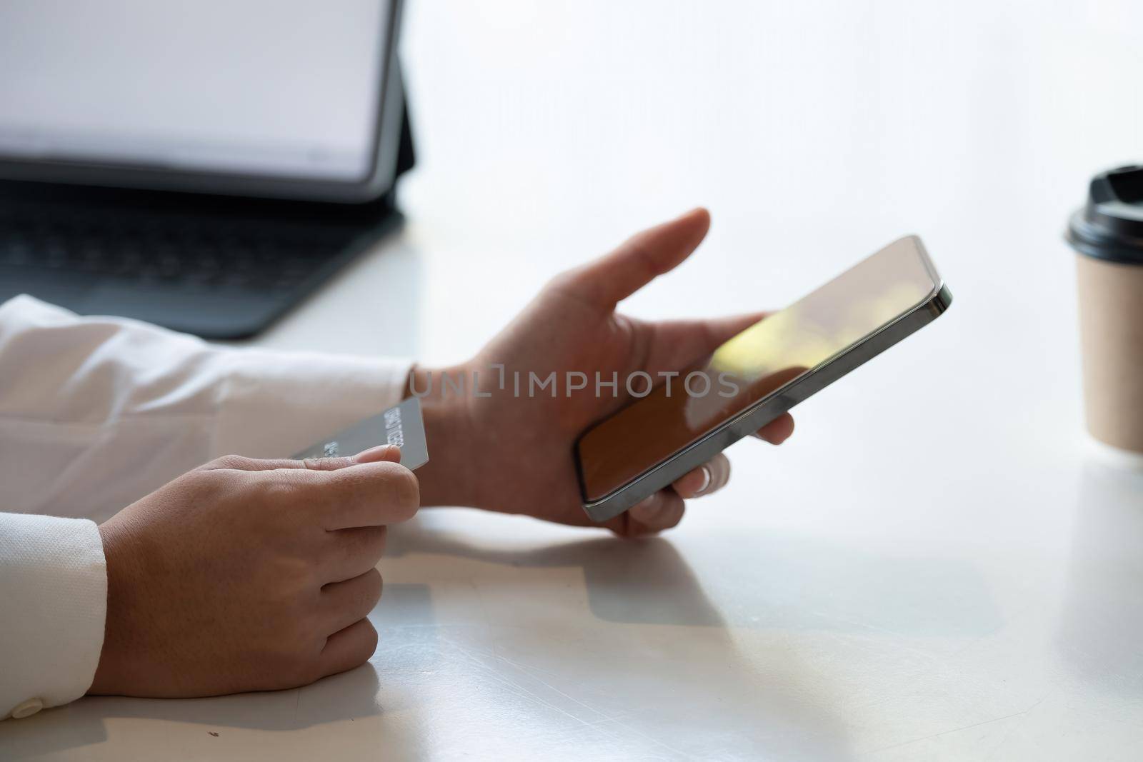 Close up hand of woman shopping online with credit card using smart phone at cafe by nateemee