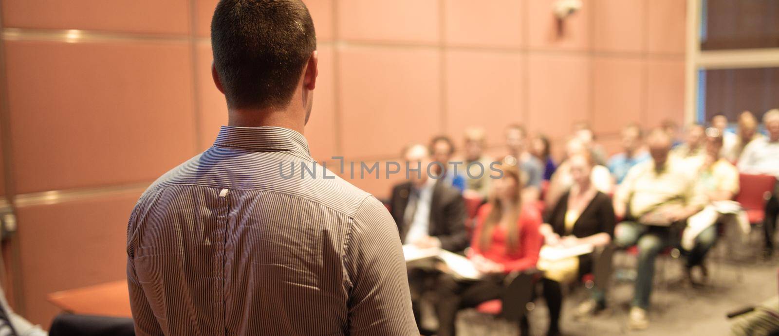 Speaker giving a talk on corporate business conference. Unrecognizable people in audience at conference hall. Business and Entrepreneurship event.