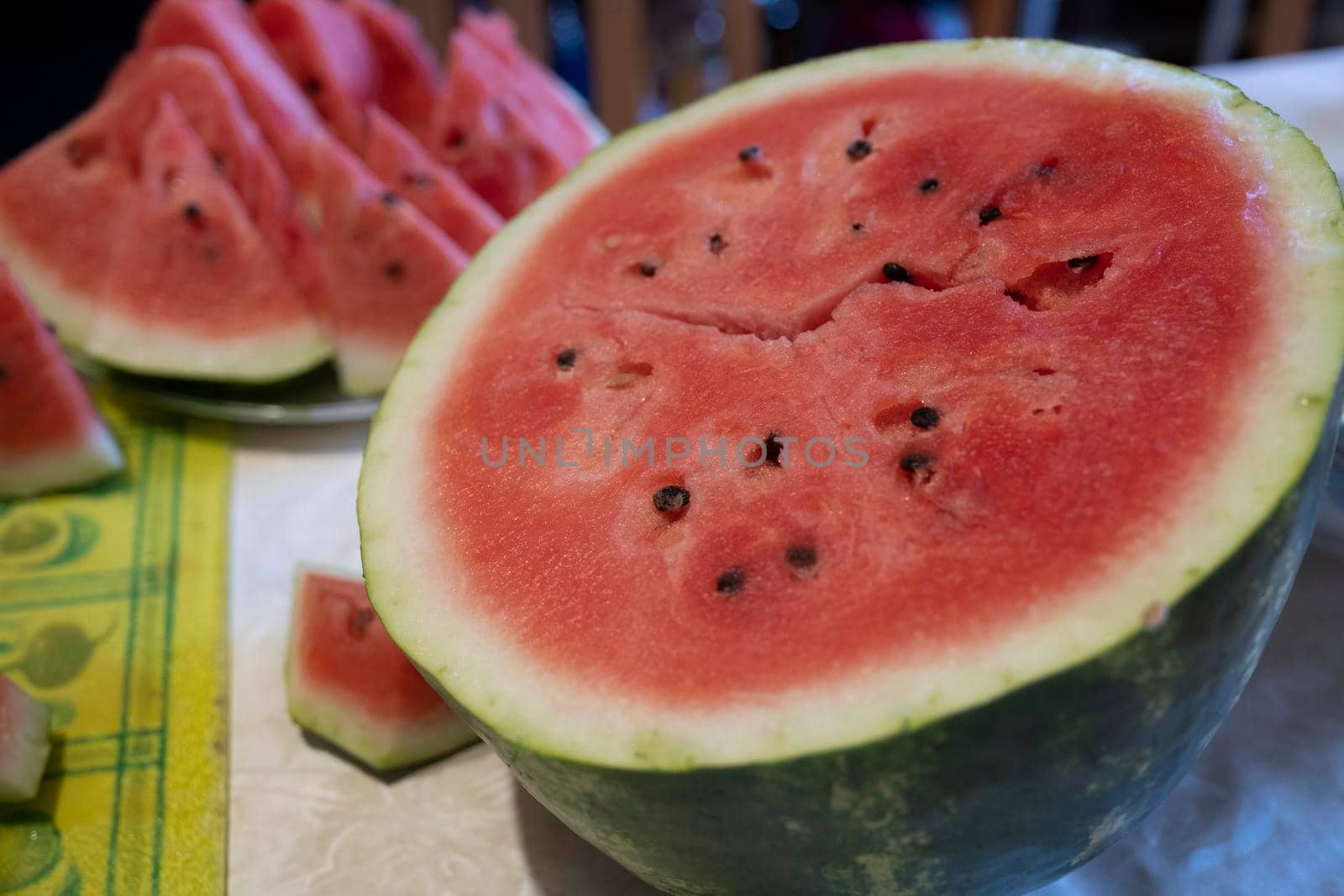 A woman's hand cuts watermelon fruit with a knife on a cutting Board in the kitchen.