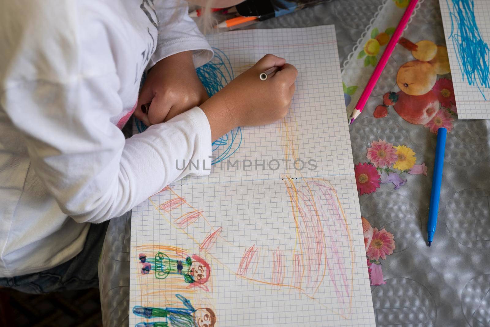 Happy child draws fairy-tale character with felt-tip pens on paper.