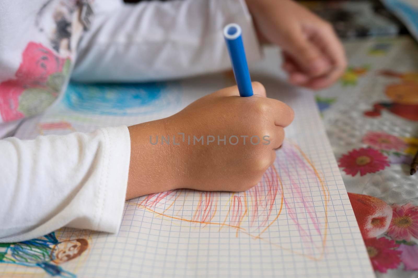 Happy child draws fairy-tale character with felt-tip pens on paper.