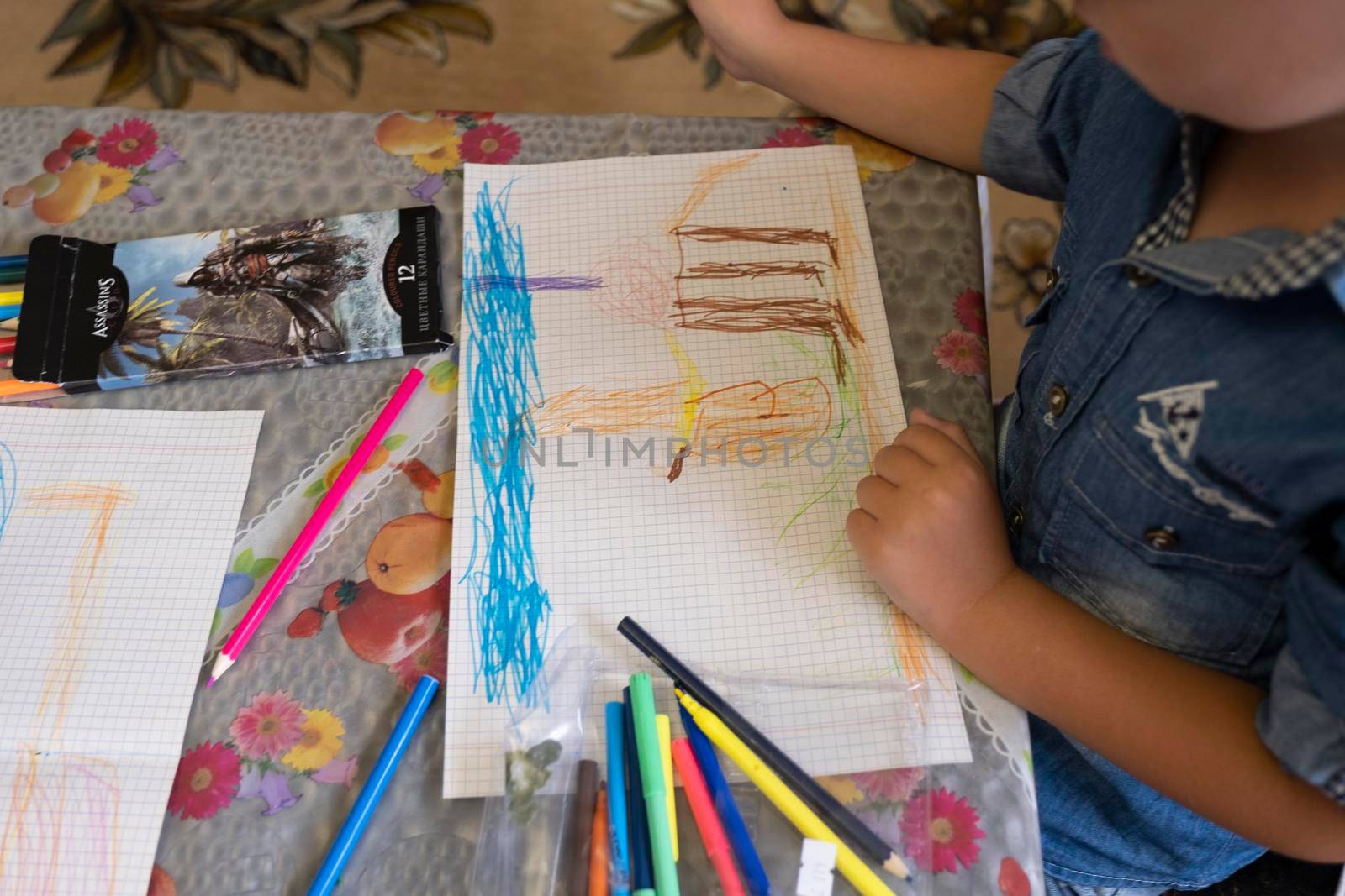 Happy child draws fairy-tale character with felt-tip pens on paper.