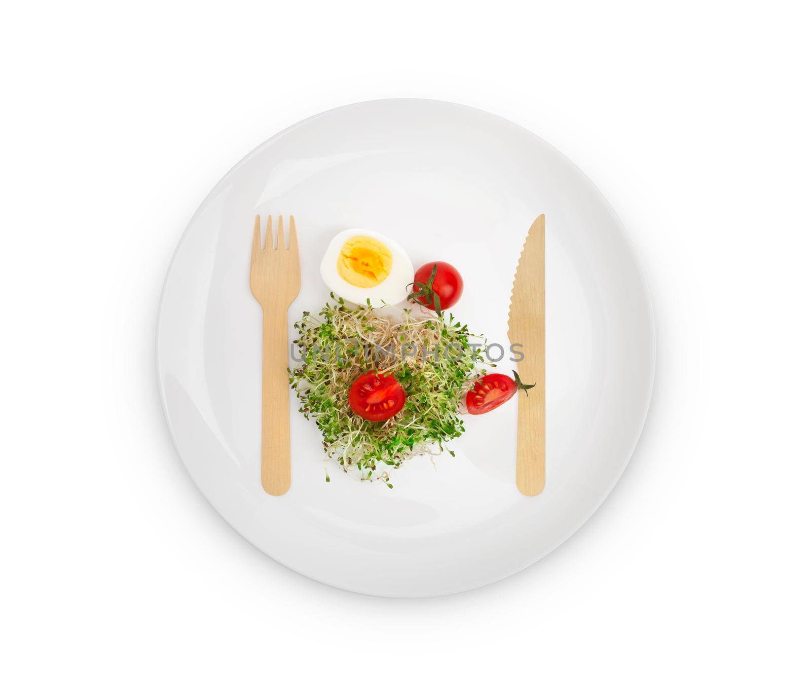 Heap of alfalfa sprouts on a white plate with a wooden fork and knife. Healthy food concept. Isolated on white background with clipping path.