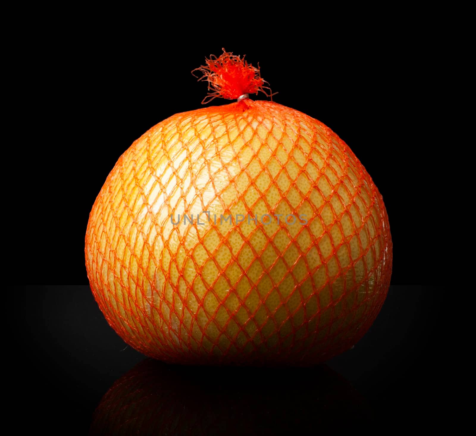 Pomelo citrus fruit in a shipping orange package close up isolated on a black background