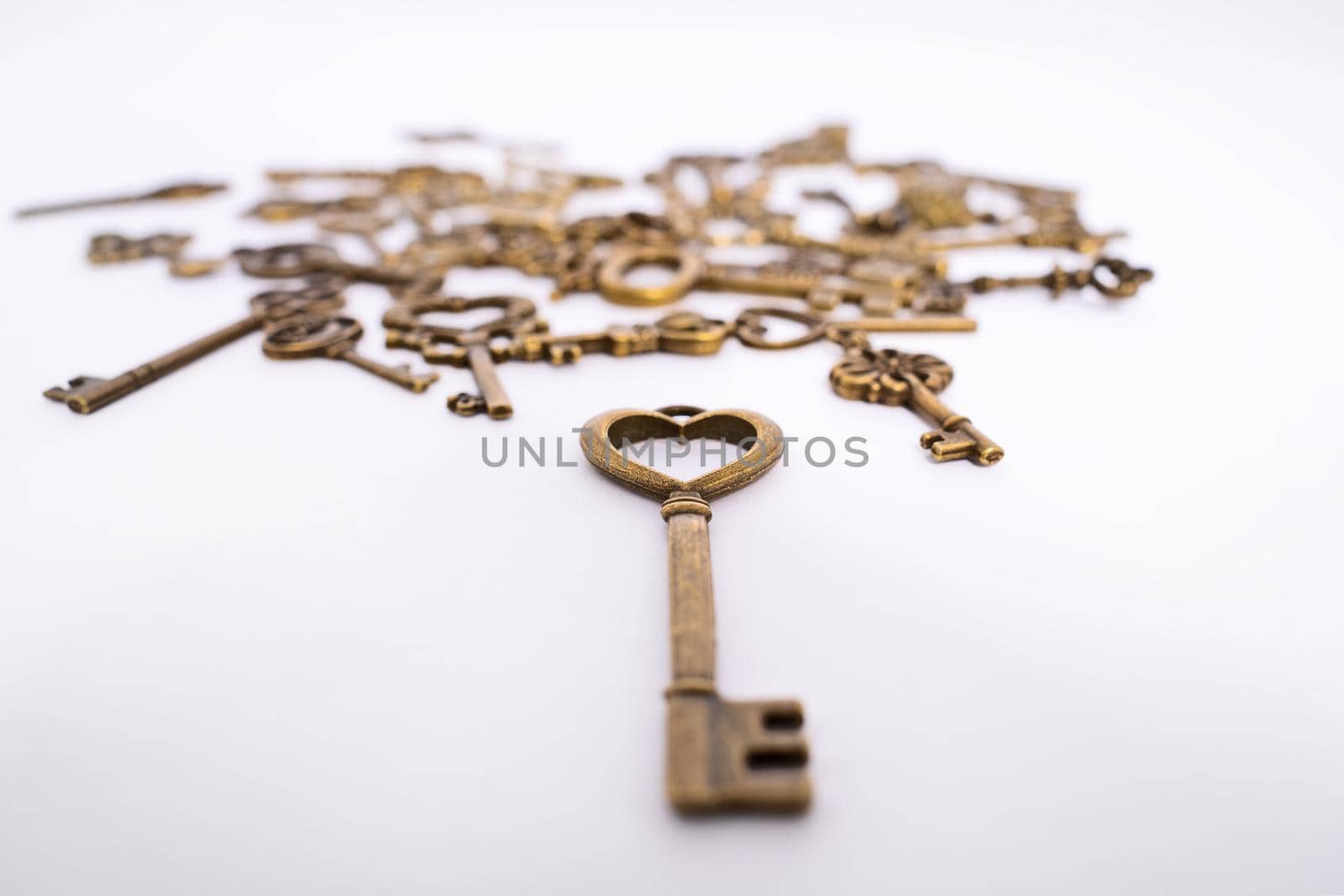 Close up of a heart shaped vintage key with collection of other keys in the background. Love symbol. Valentine’s day, love, marriage concept. Key to my heart concept. Selective focus.