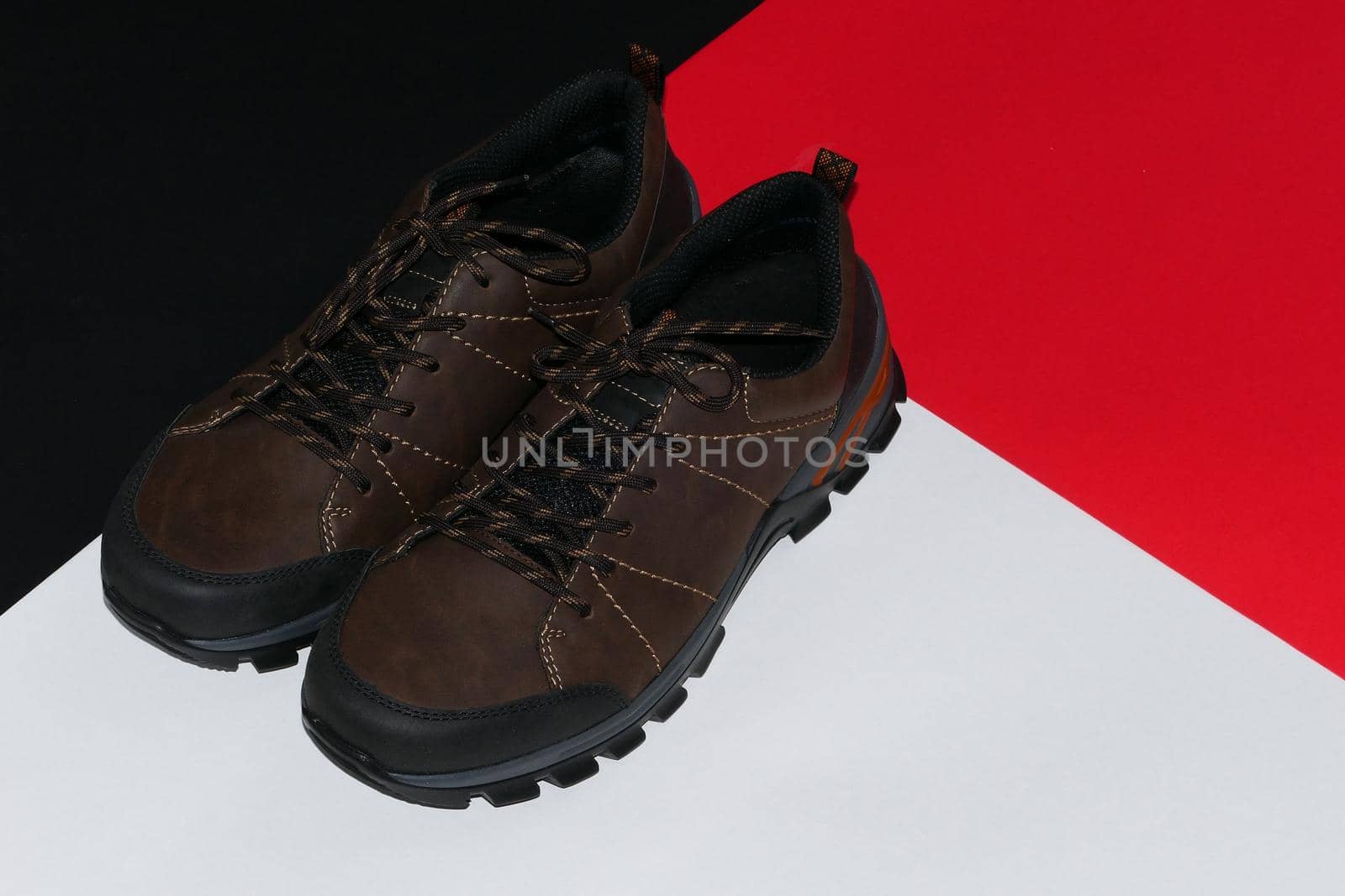 Stylish men's sneakers or leather brown shoes on a colored background.