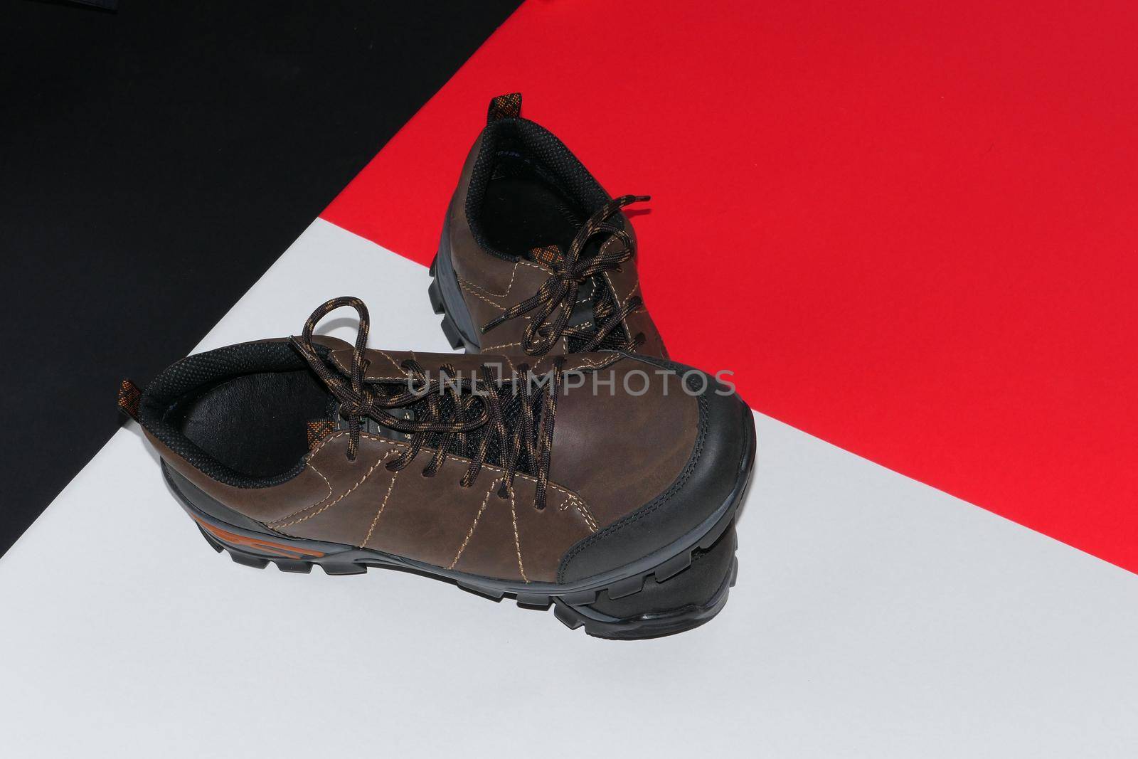 Stylish men's sneakers or leather brown shoes on a colored background.