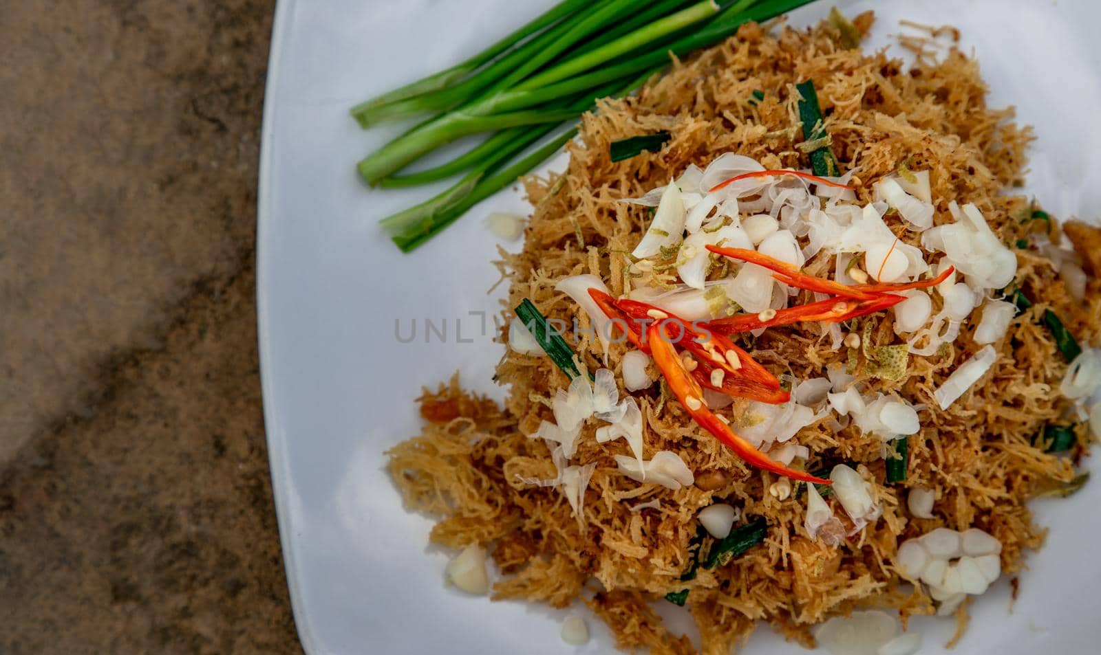 Asian eating food, Mee Grob is an sweet and sour crispy noodles, made from Thai rice noodle with sweet and sour sauce on white plate, Sweet & Sour Crispy Rice Noodles, Close up.