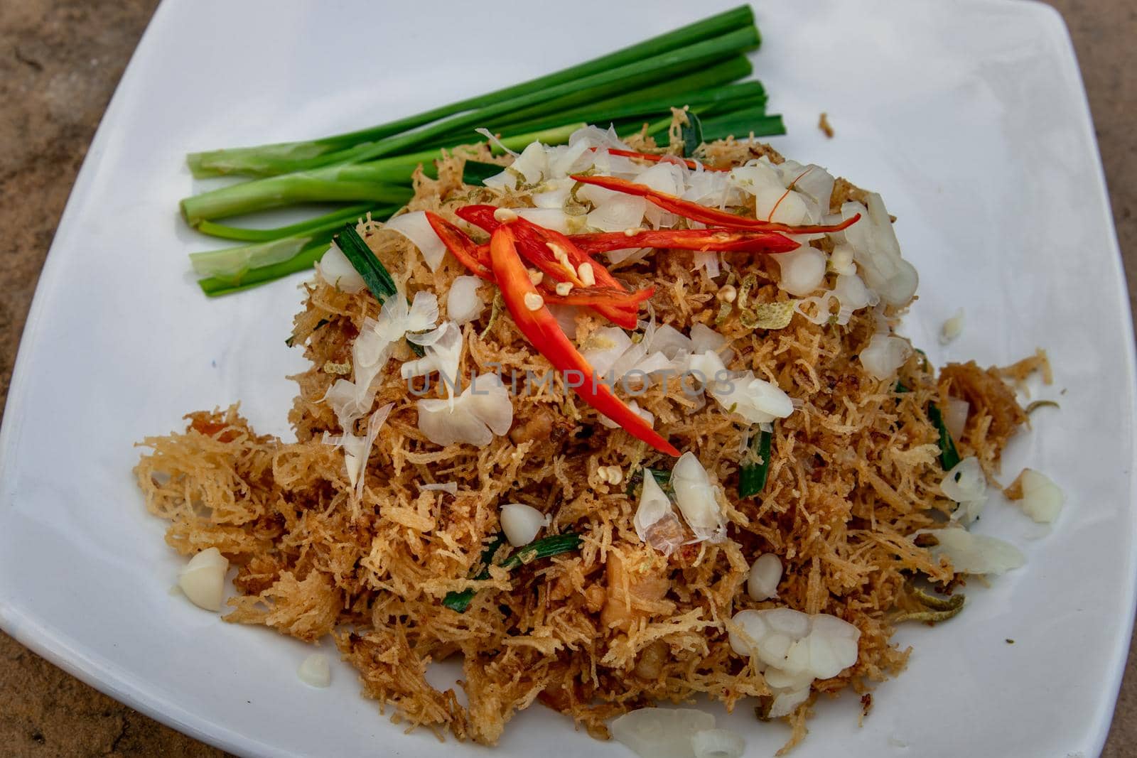 Asian eating food, Mee Grob is an sweet and sour crispy noodles, made from Thai rice noodle with sweet and sour sauce on white plate, Sweet & Sour Crispy Rice Noodles, Oblique view from the top.