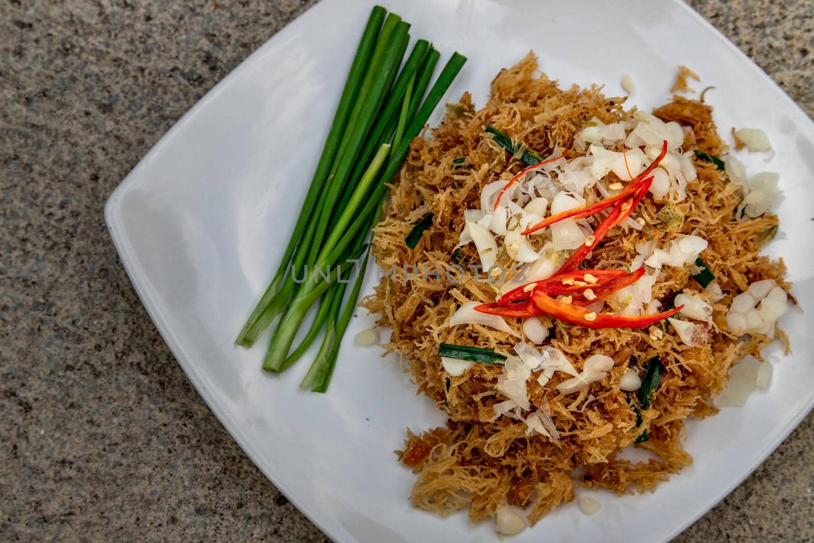 Asian eating food, Mee Grob is an sweet and sour crispy noodles, made from Thai rice noodle with sweet and sour sauce on white plate, Sweet & Sour Crispy Rice Noodles, Top view.