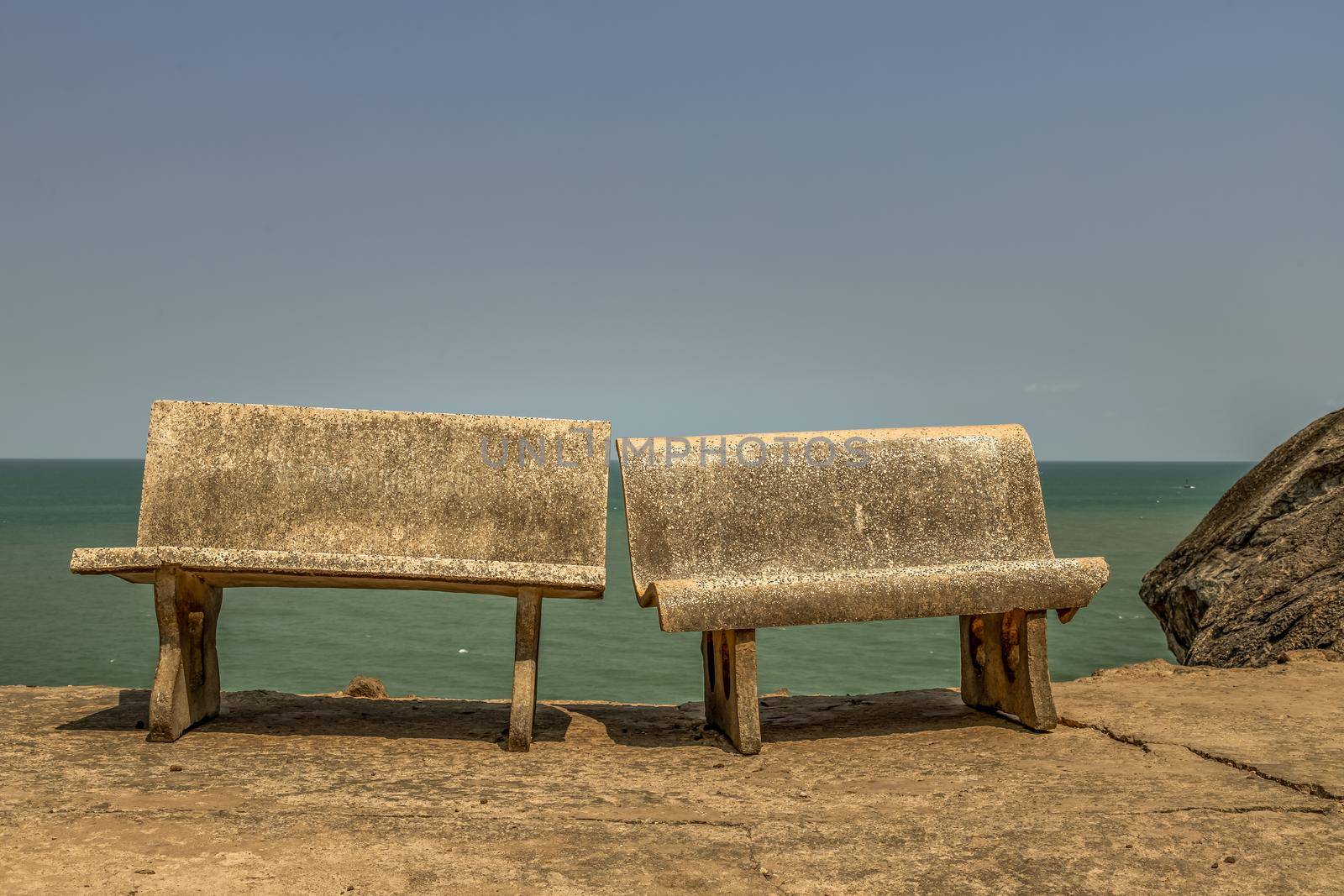 Old two polished stone chairs Leaning against each other by the sea. Selective focus.