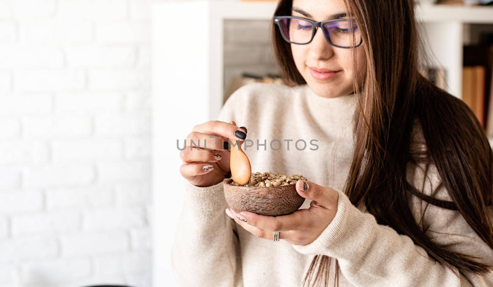 Alternative coffee brewing. Young brunette woman brewing coffee in chemex, smelling green coffee beans