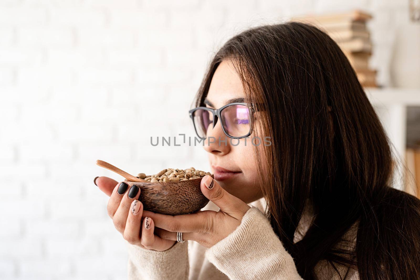 Alternative coffee brewing. Young brunette woman brewing coffee in chemex, smelling green coffee beans