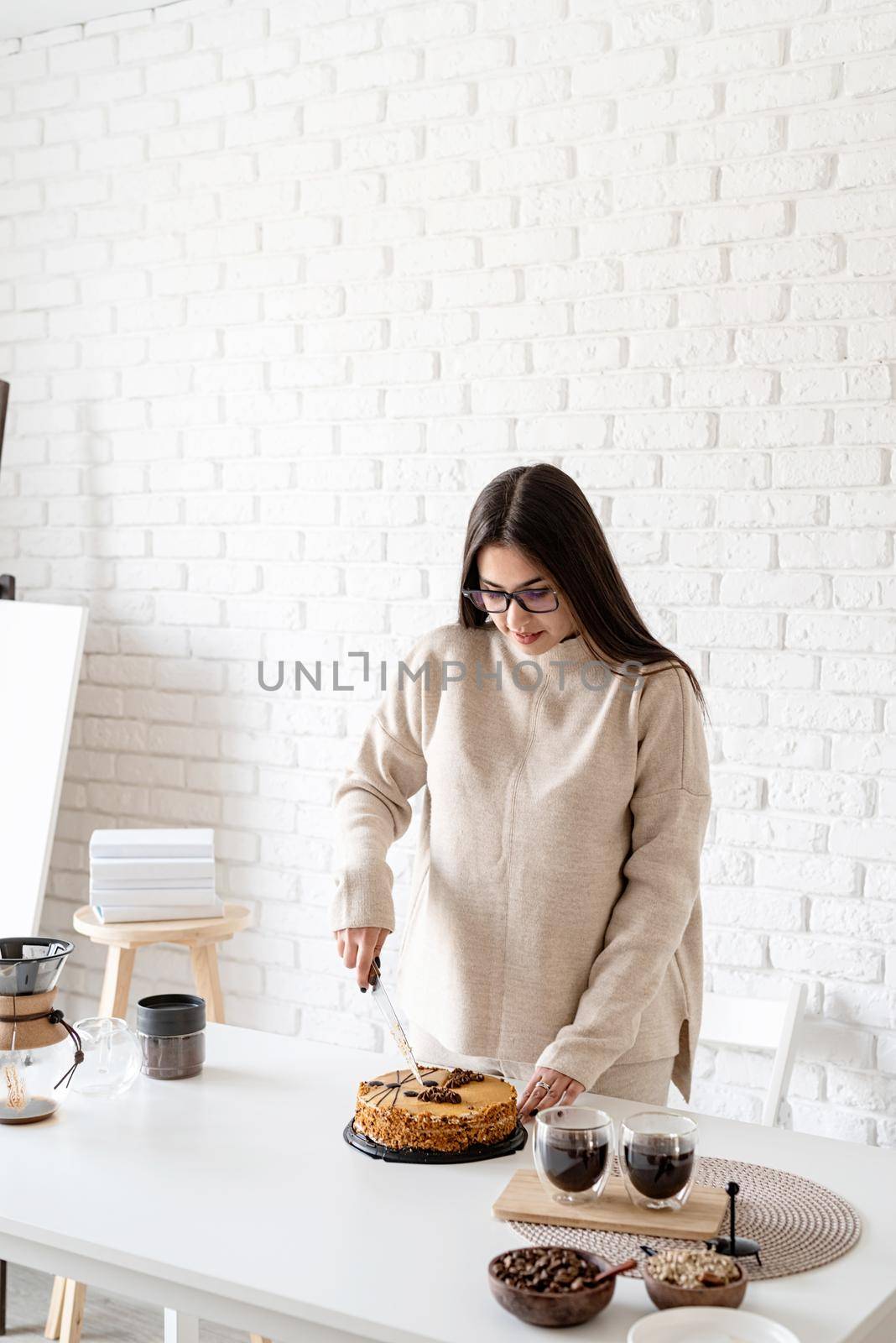 Alternative coffee brewing. Young woman brewing coffee in chemex and cutting a cake