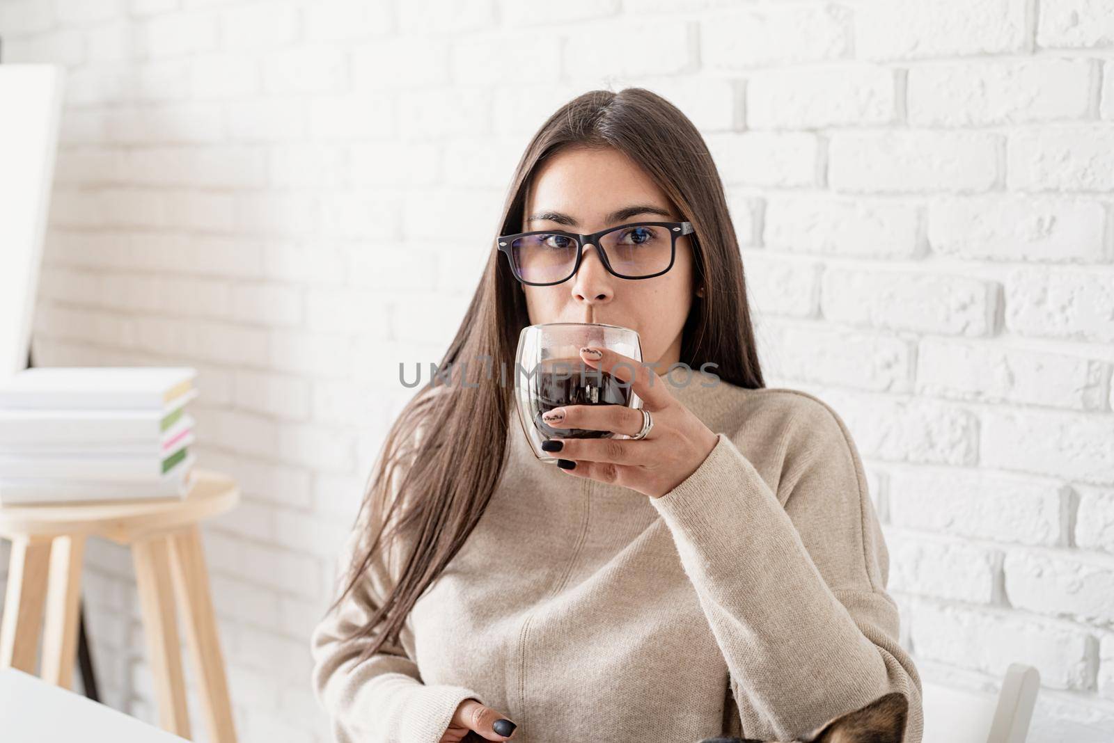 Alternative coffee brewing. Young brunette woman drinking hot black coffee sitting at the white table