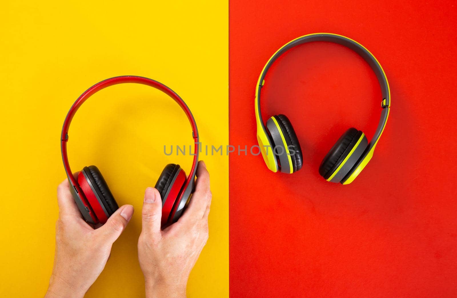 hand holding a headphones on red and yellow background. by tehcheesiong