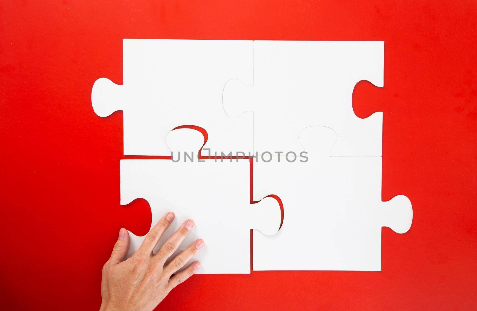 Concept of business,hand solving a puzzle piece on red background.