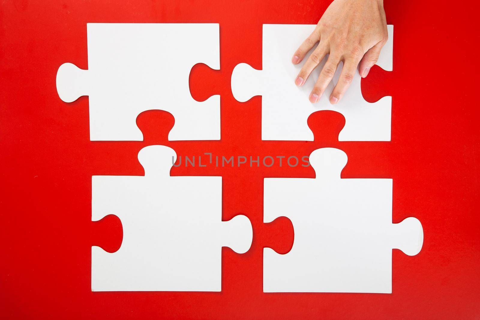 Concept of business,hand solving a puzzle piece on red background.