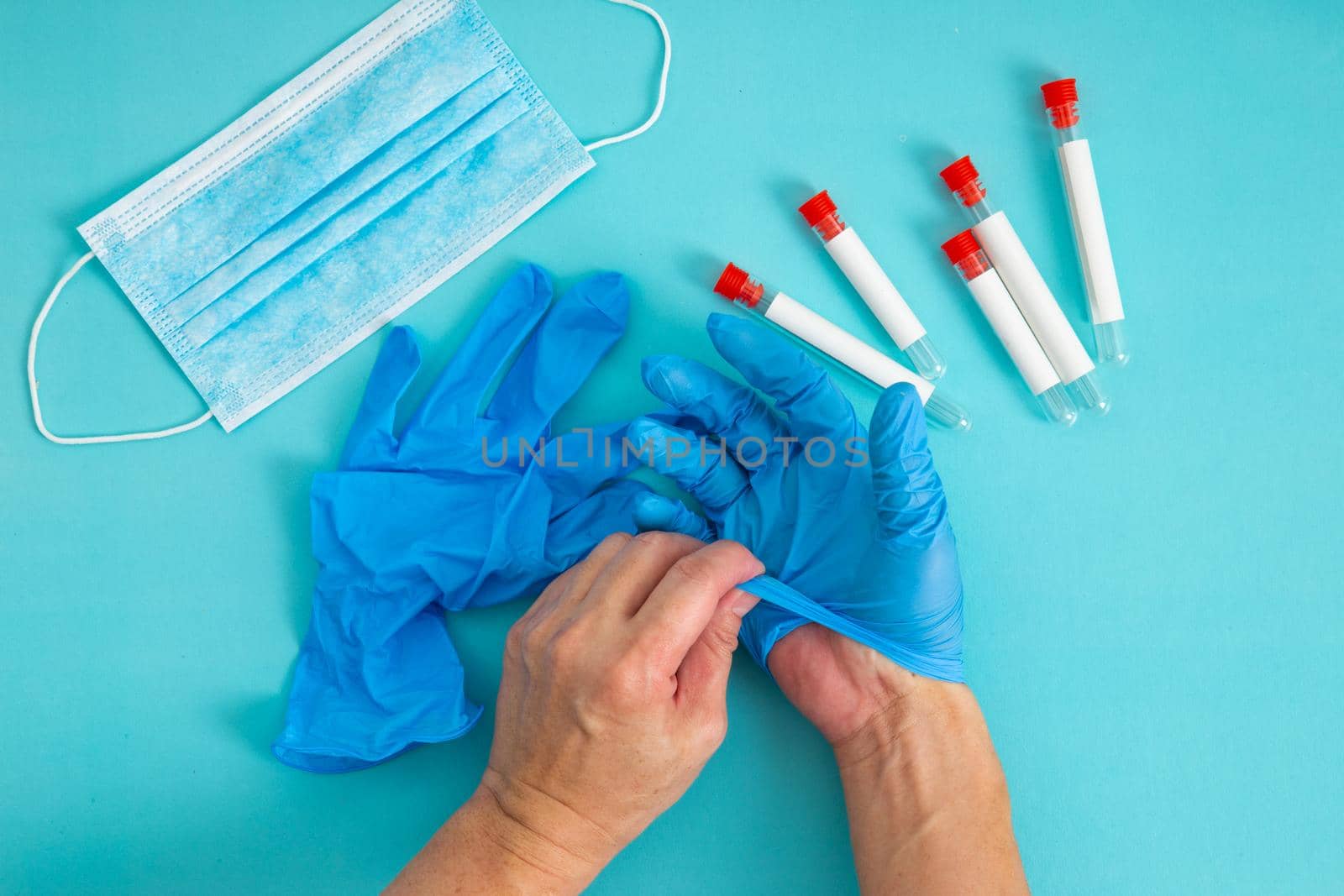 hands remove glove on blue background. The concept of treatment, protection from viruses, flu, recovery, stop coronavirus.