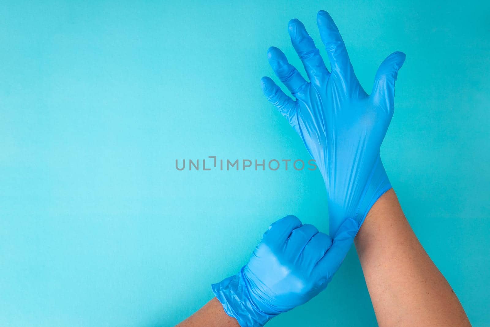 hands wear rubber gloves on a blue background by tehcheesiong
