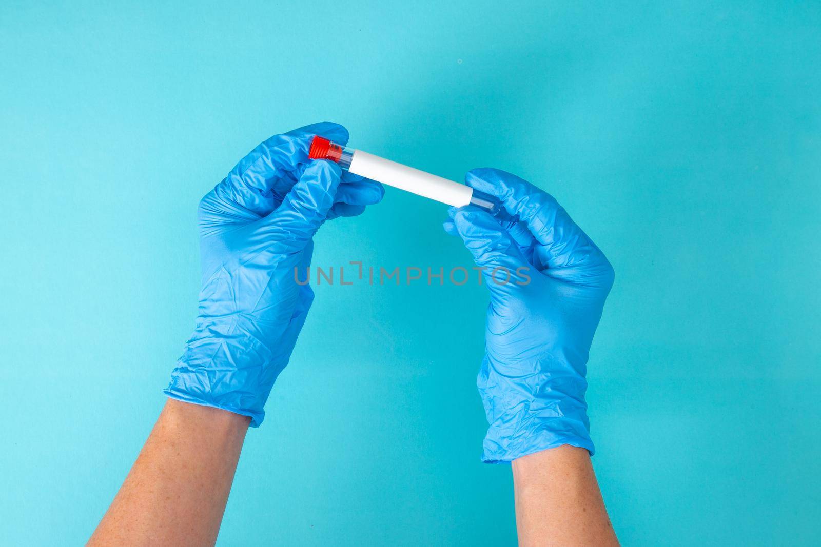 hand in blue gloves holding a test tube on blue background