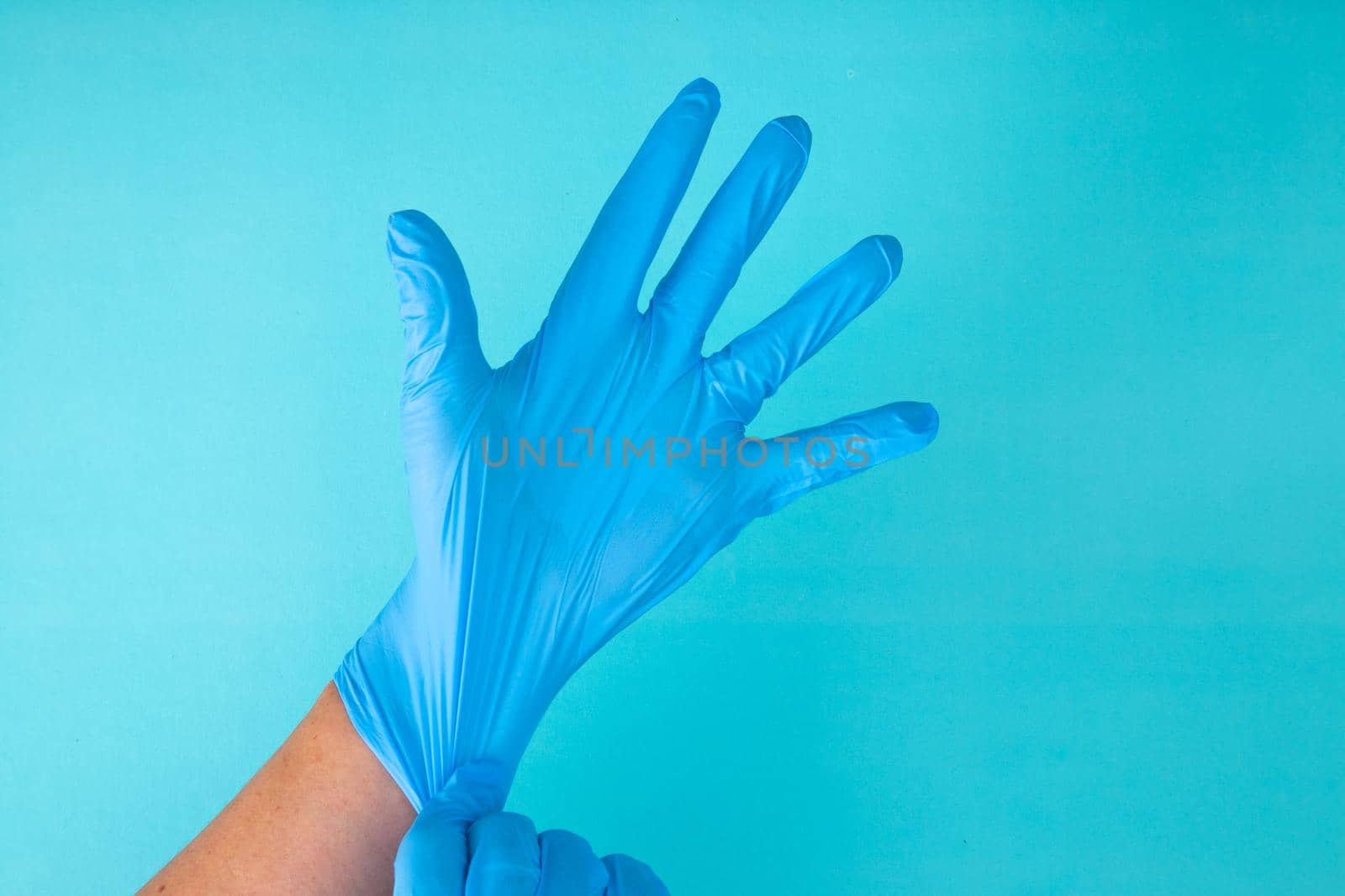 Doctor's hands wear rubber gloves on a blue background