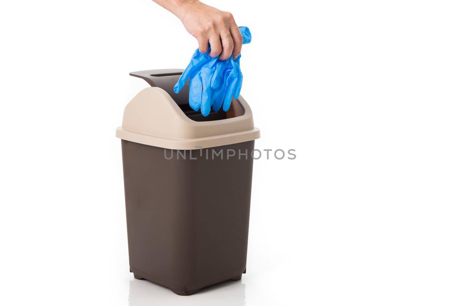 hand throws medical glove into the trash.