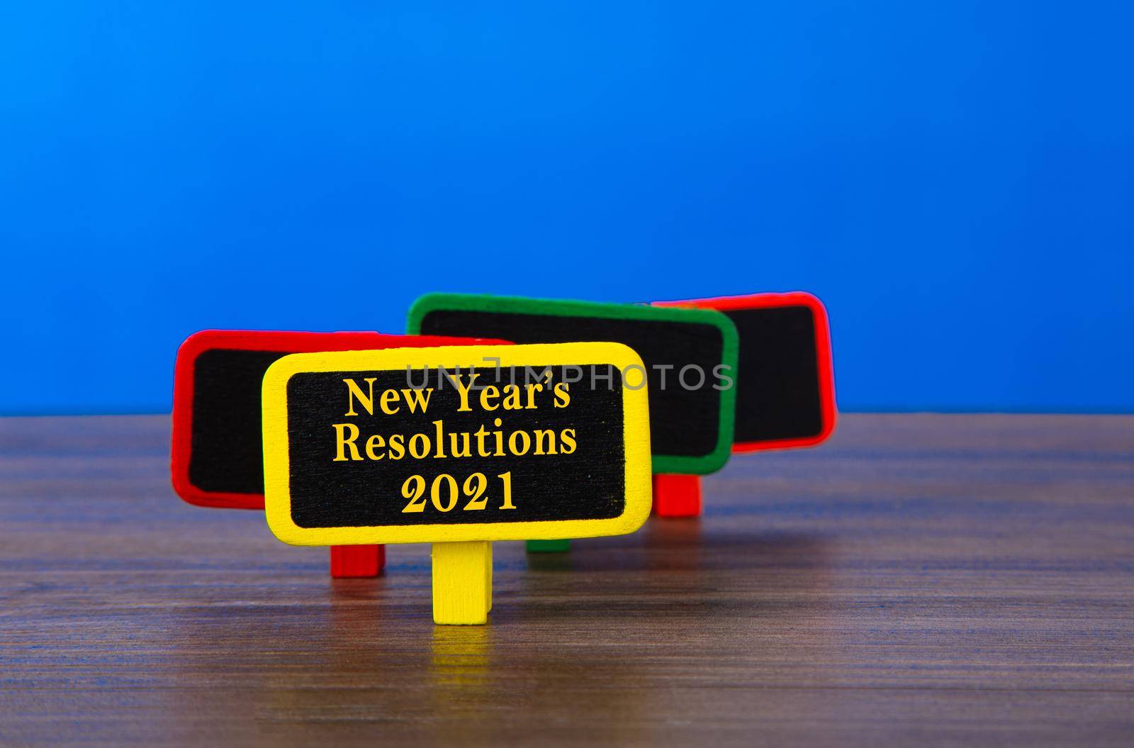 A wooden tag with the word New Year's Resolution 2021 on table with blue background