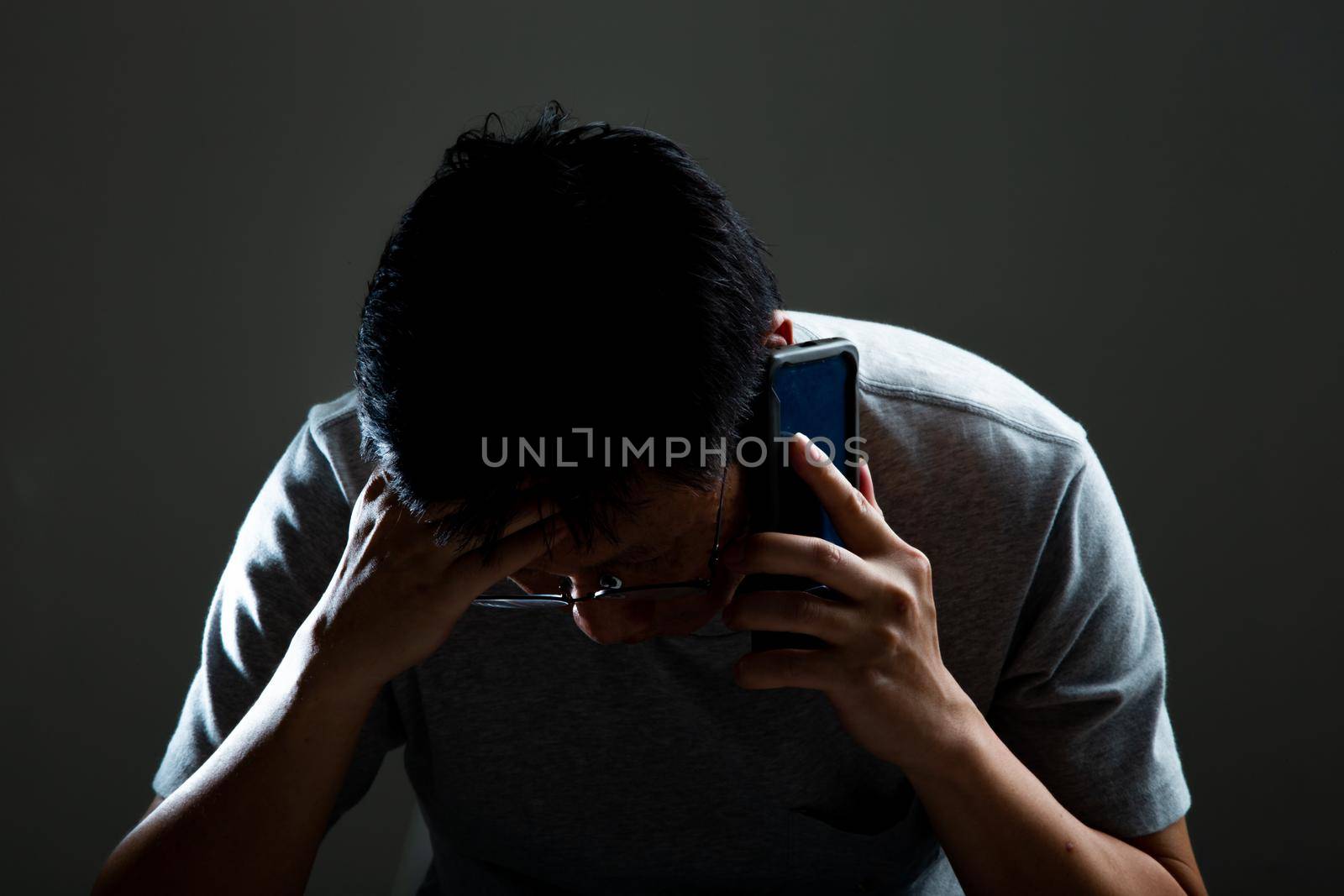 Sad and depressed man received a bad news from his phone by tehcheesiong