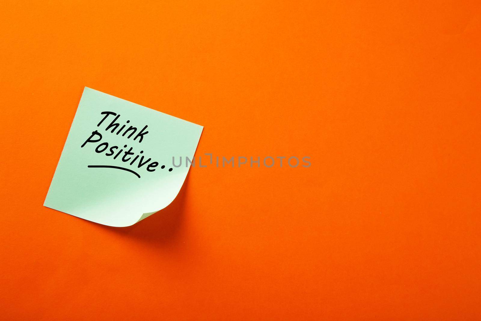 Motivational think positive word on note pads on orange background