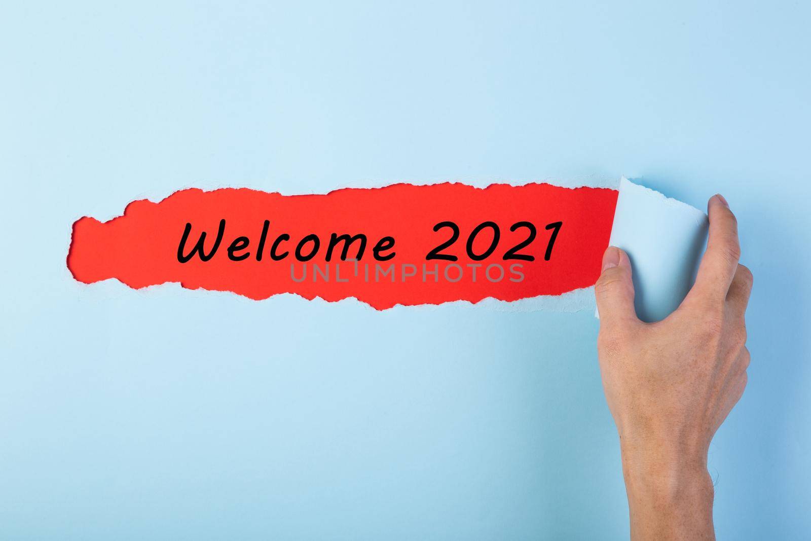Hand tearing color paper with word Welcome Year 2021. New Year Concept