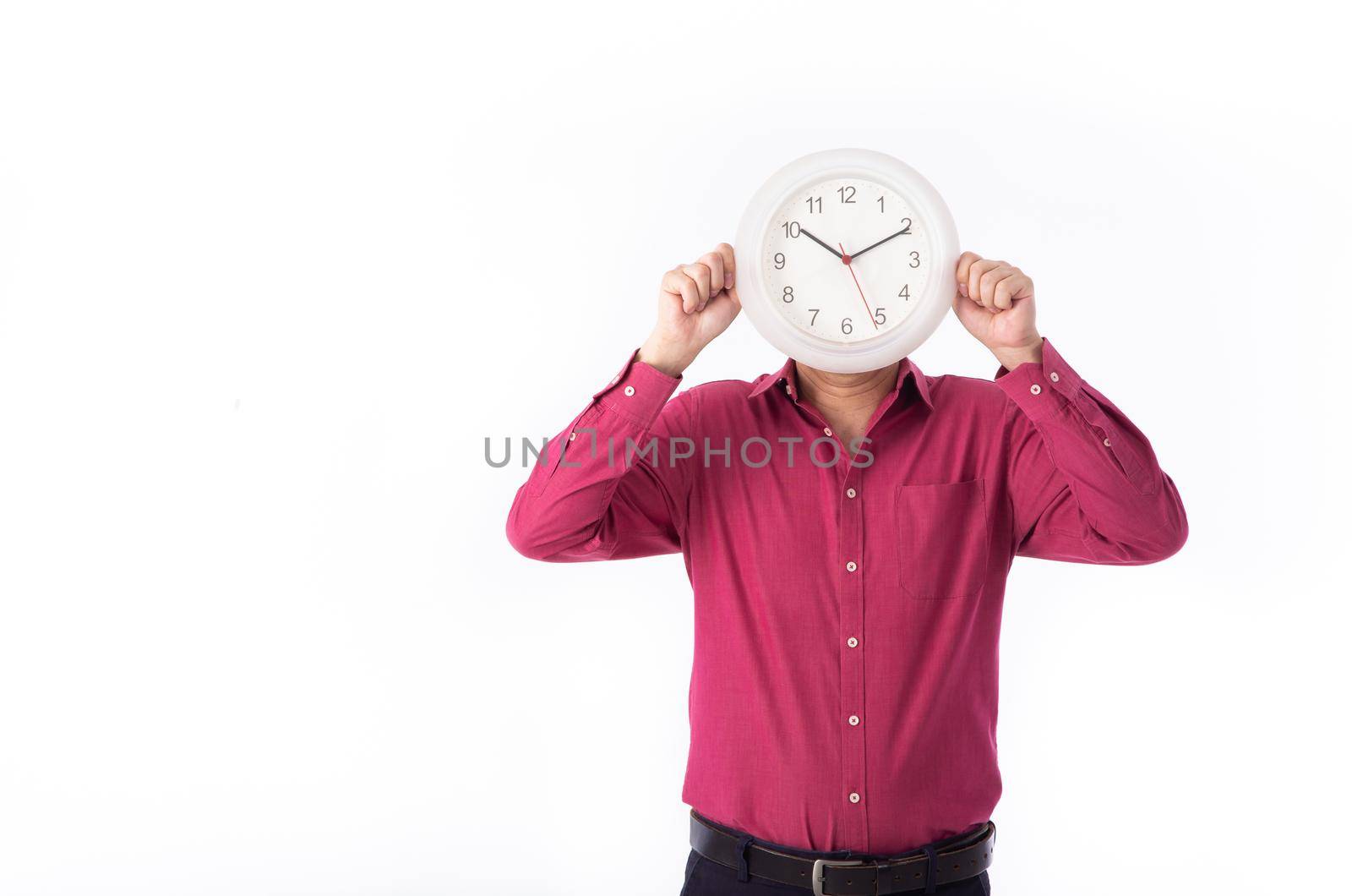 A businessman holding a clock right in front of his face. isolated on white background.