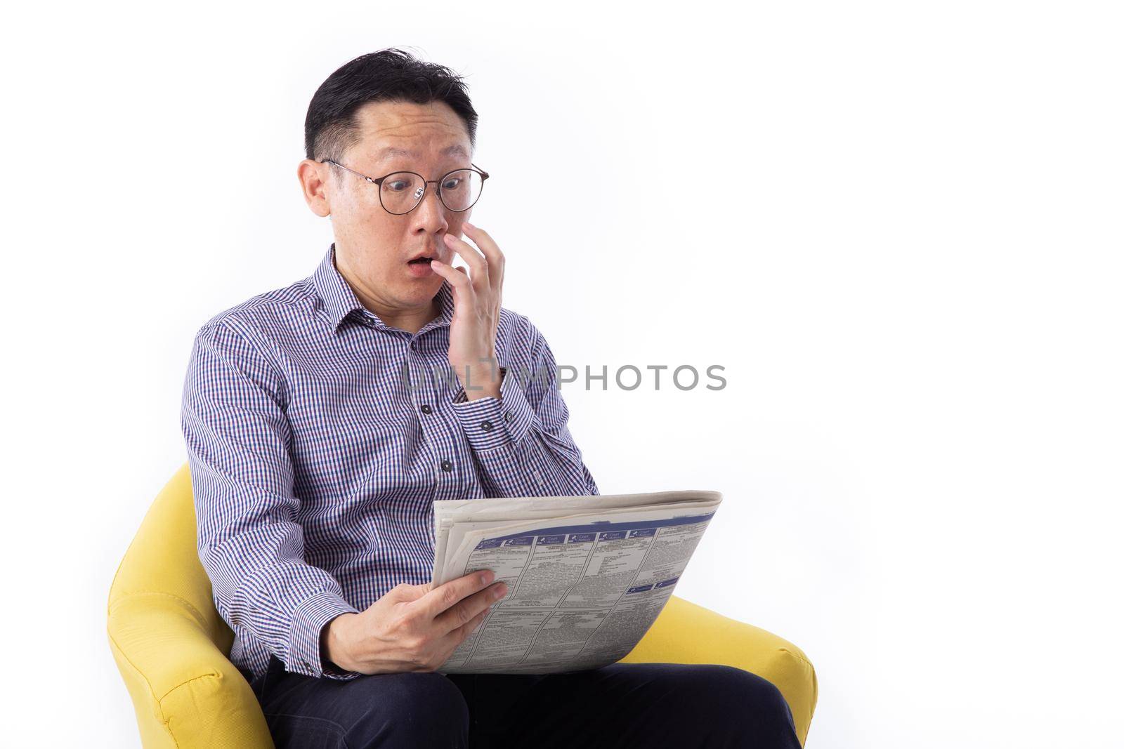 Surprised man reading the news seated on a bench isolated on white background