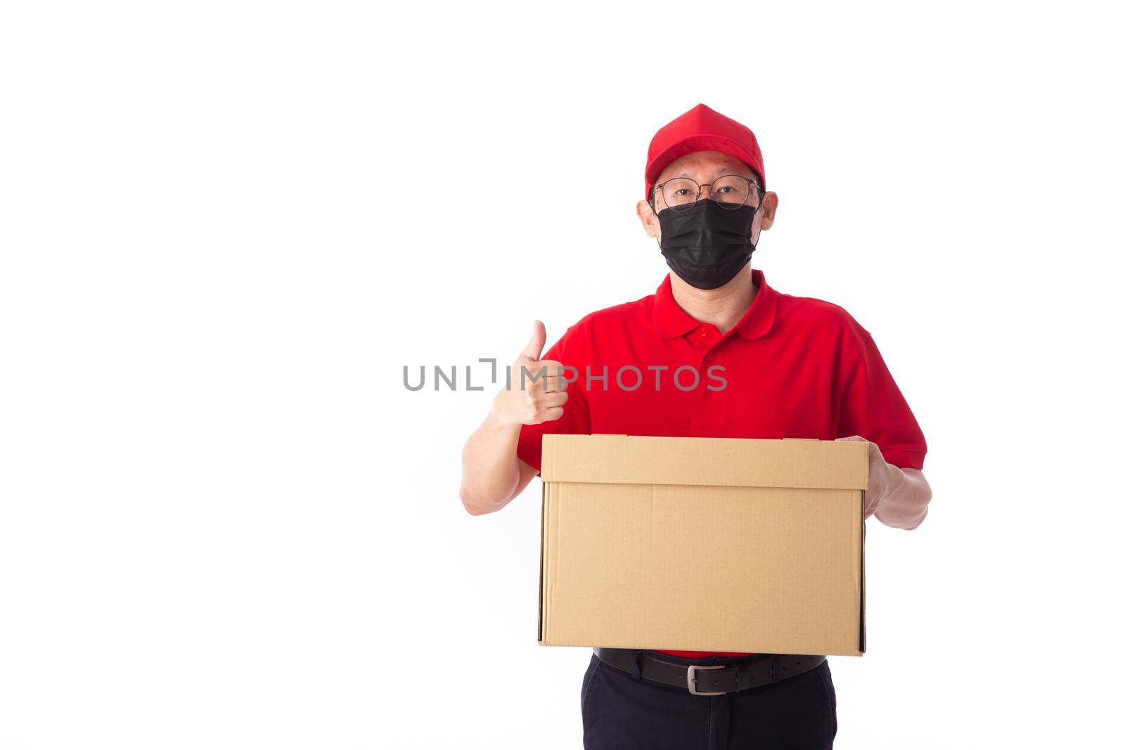 young Asian delivery man in red uniform with  face mask, carrry cardboard box in hands isolated on white background. Delivery concept