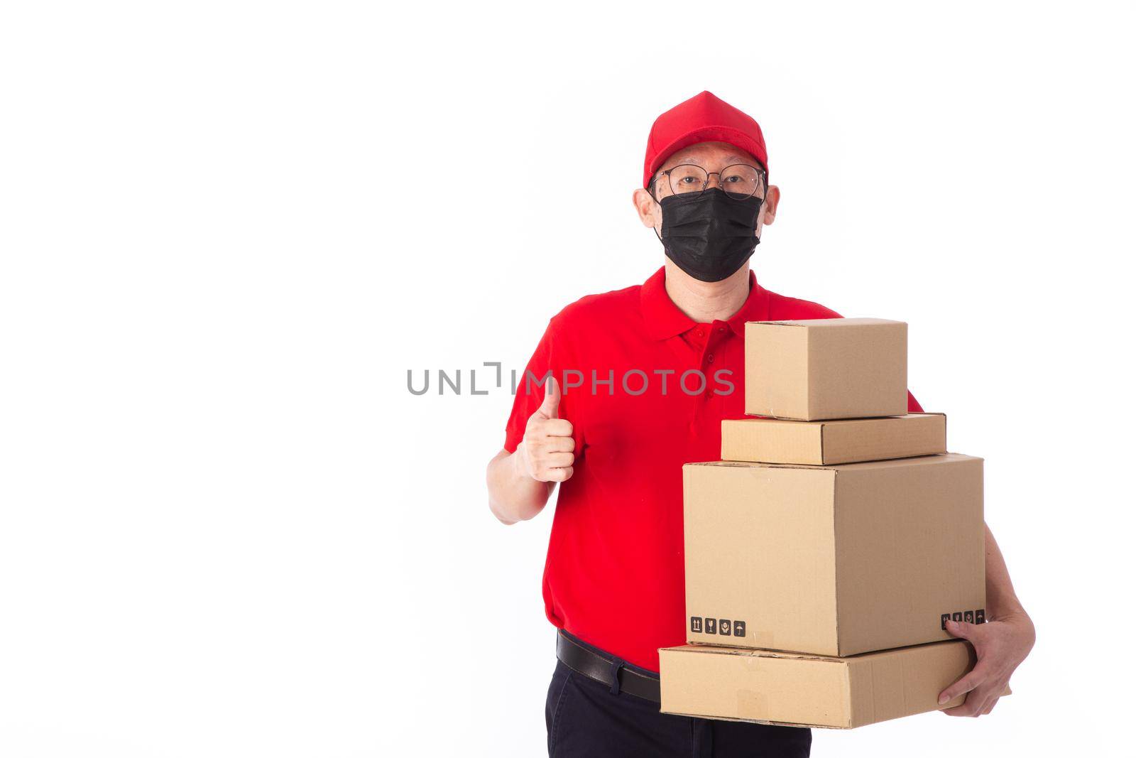 young Asian delivery man in red uniform with  face mask, carrry cardboard box in hands isolated on white background. Delivery concept