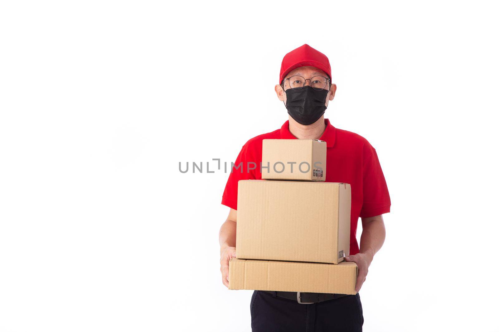 young Asian delivery man in red uniform with  face mask, carrry cardboard box in hands isolated on white background. Delivery concept