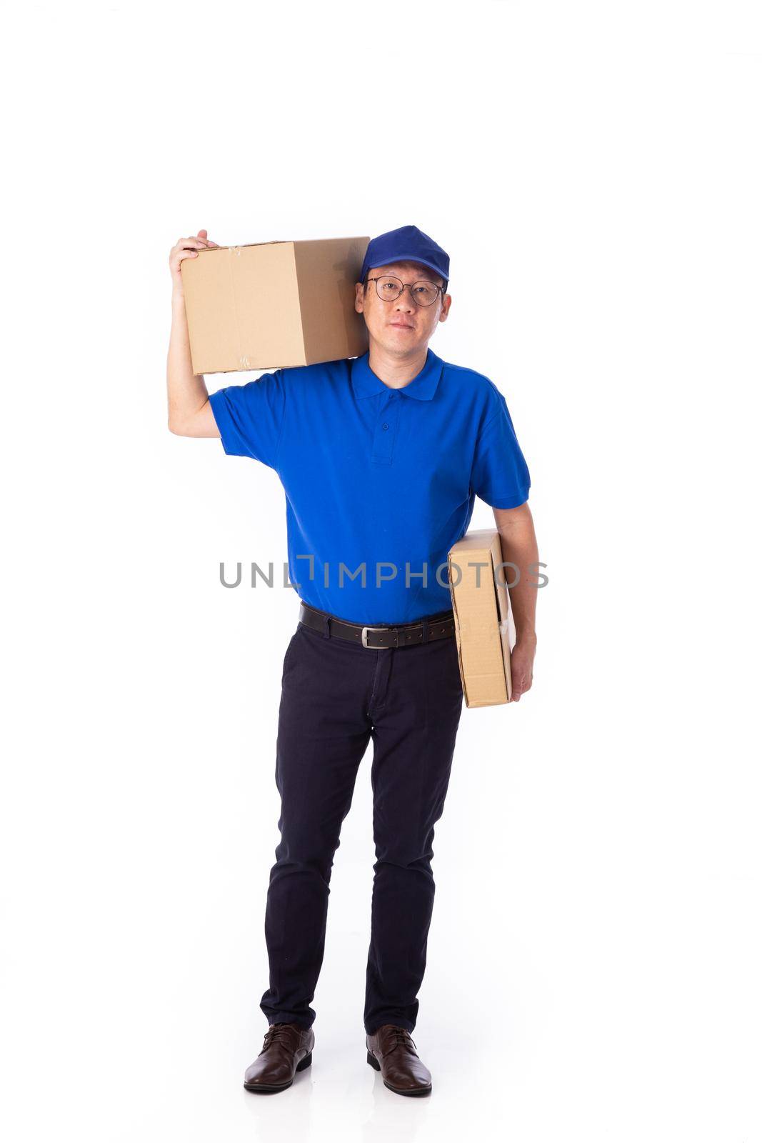 young Asian delivery man in blue uniform, carry cardboard box in hands isolated on white background. by tehcheesiong