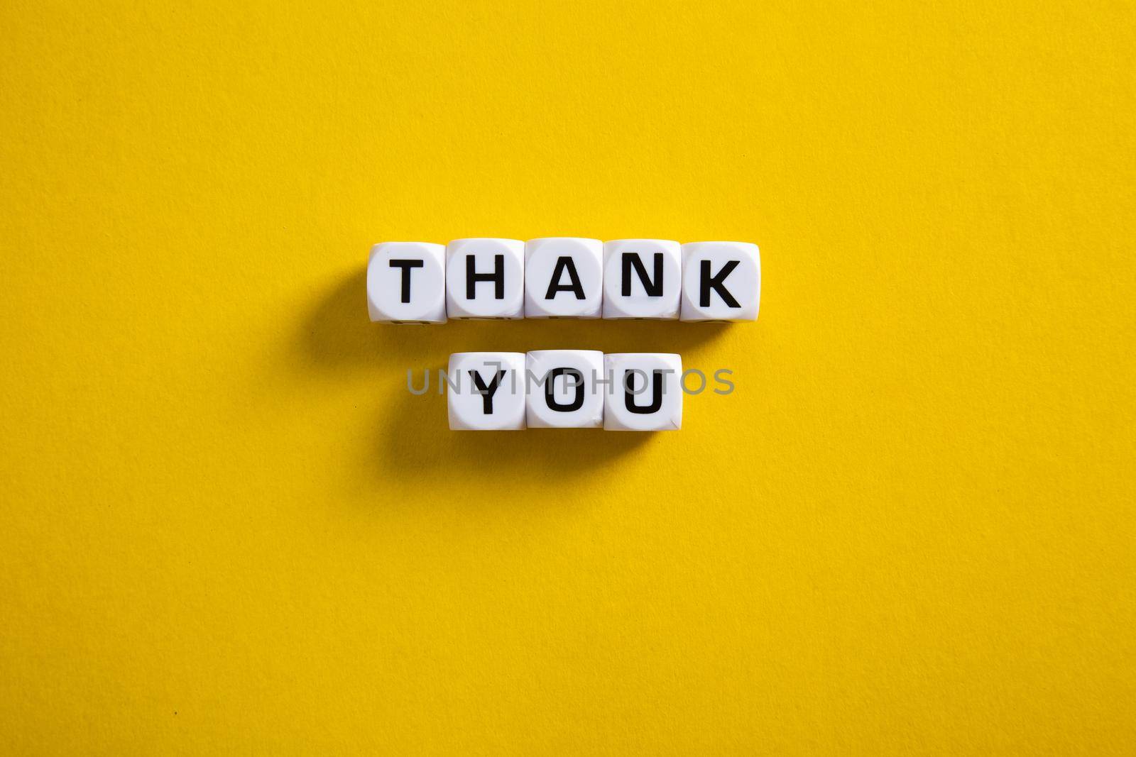 Block with word Thank You on yellow background