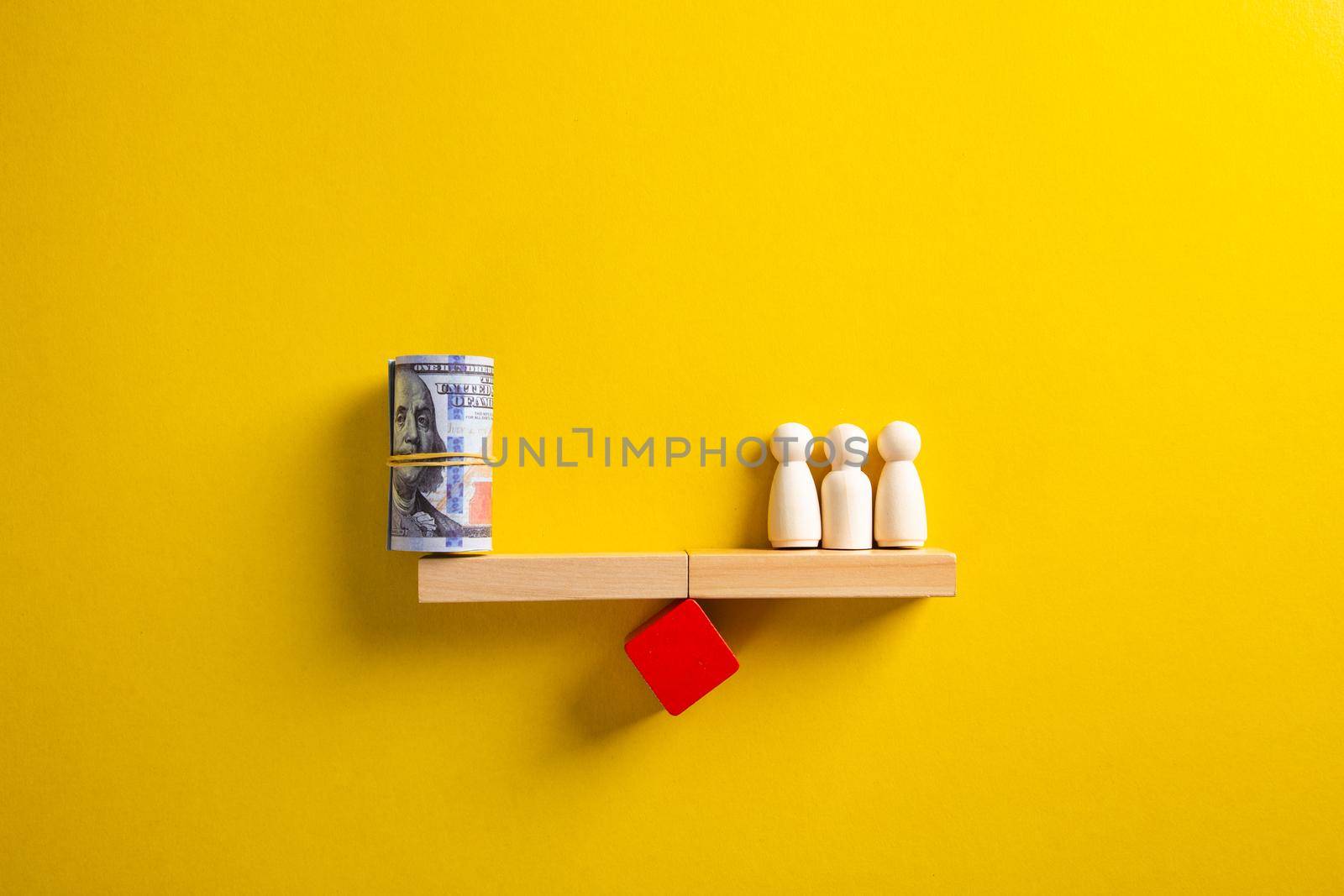 Wooden people and a bundle of dollars on the scales. Saving the company's budget. Average income, wages