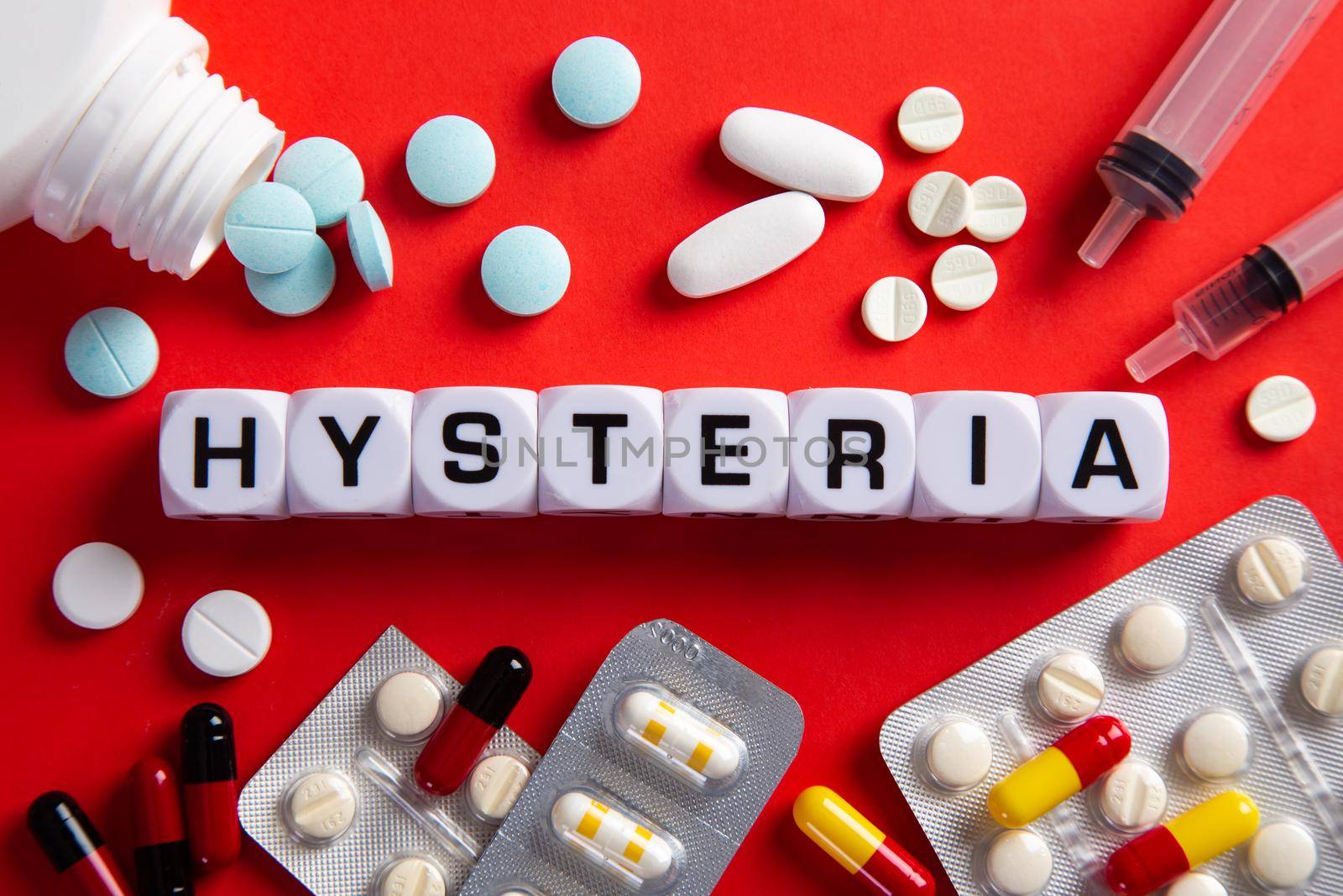 Hysteria medicine word on blocks on red background. Medical concept with pills, vitamins and syringe on the background.
