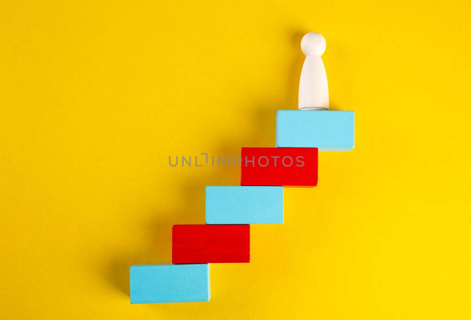 Wooden figures on yellow background. Concept of supremacy leader