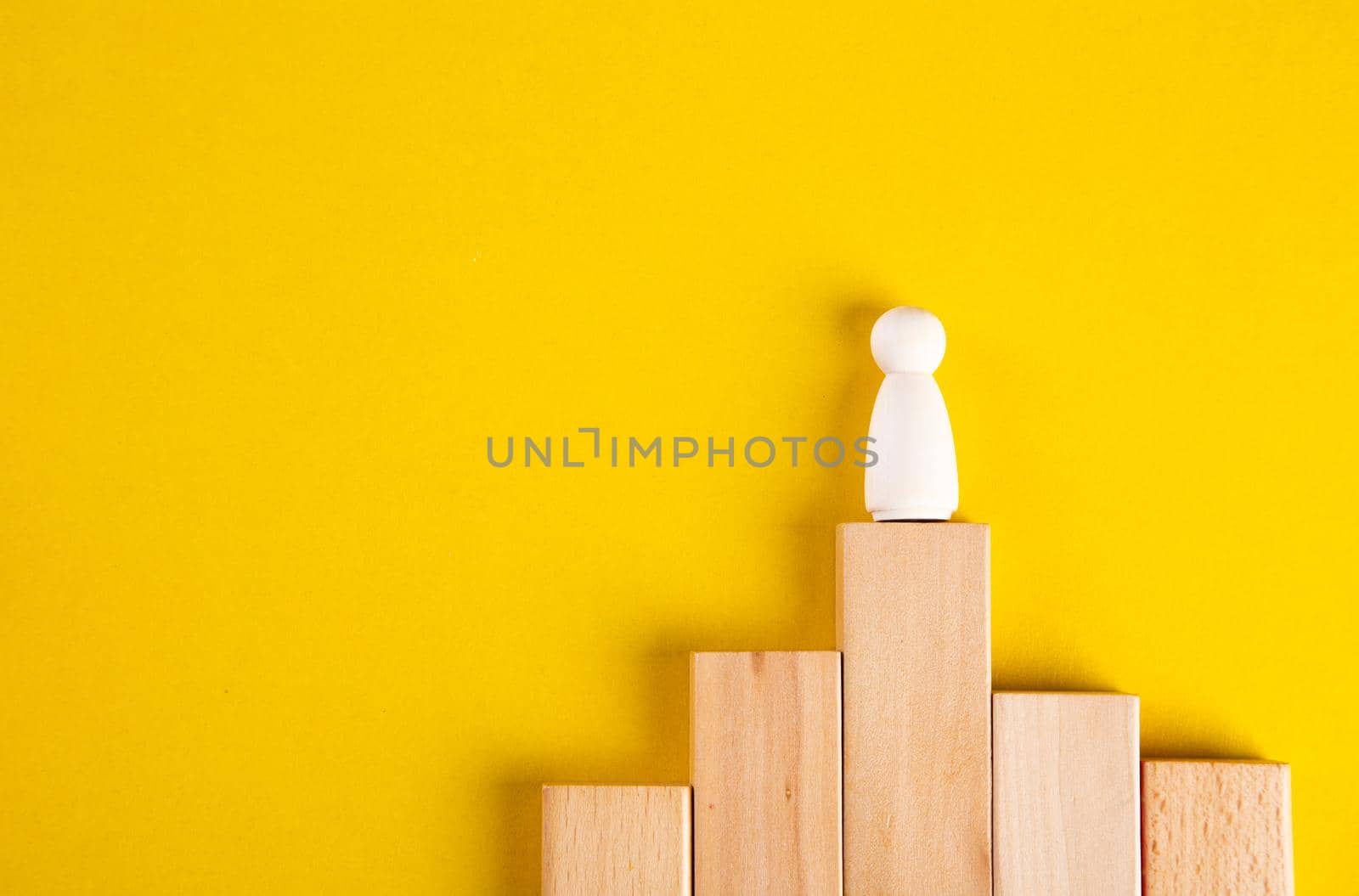 Wooden figures on yellow background. Concept of supremacy leader