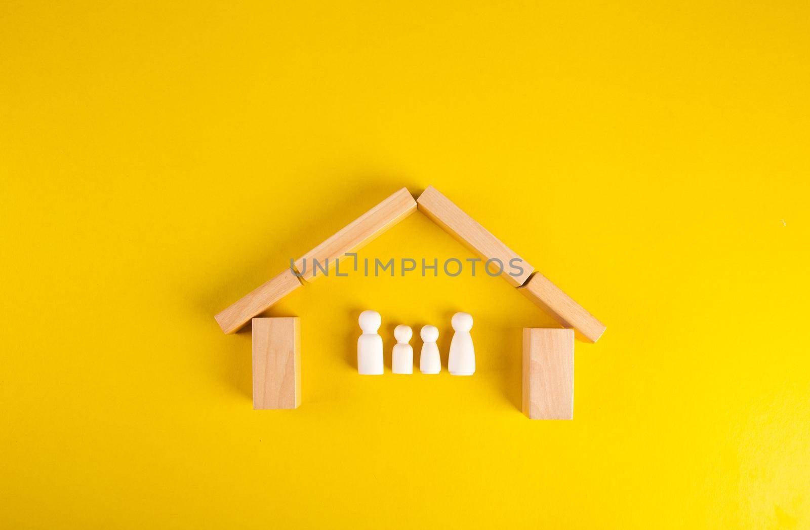 Wooden pegs in a shape of a house to shelter a family made of wooden. Family insurance protection onceptual.