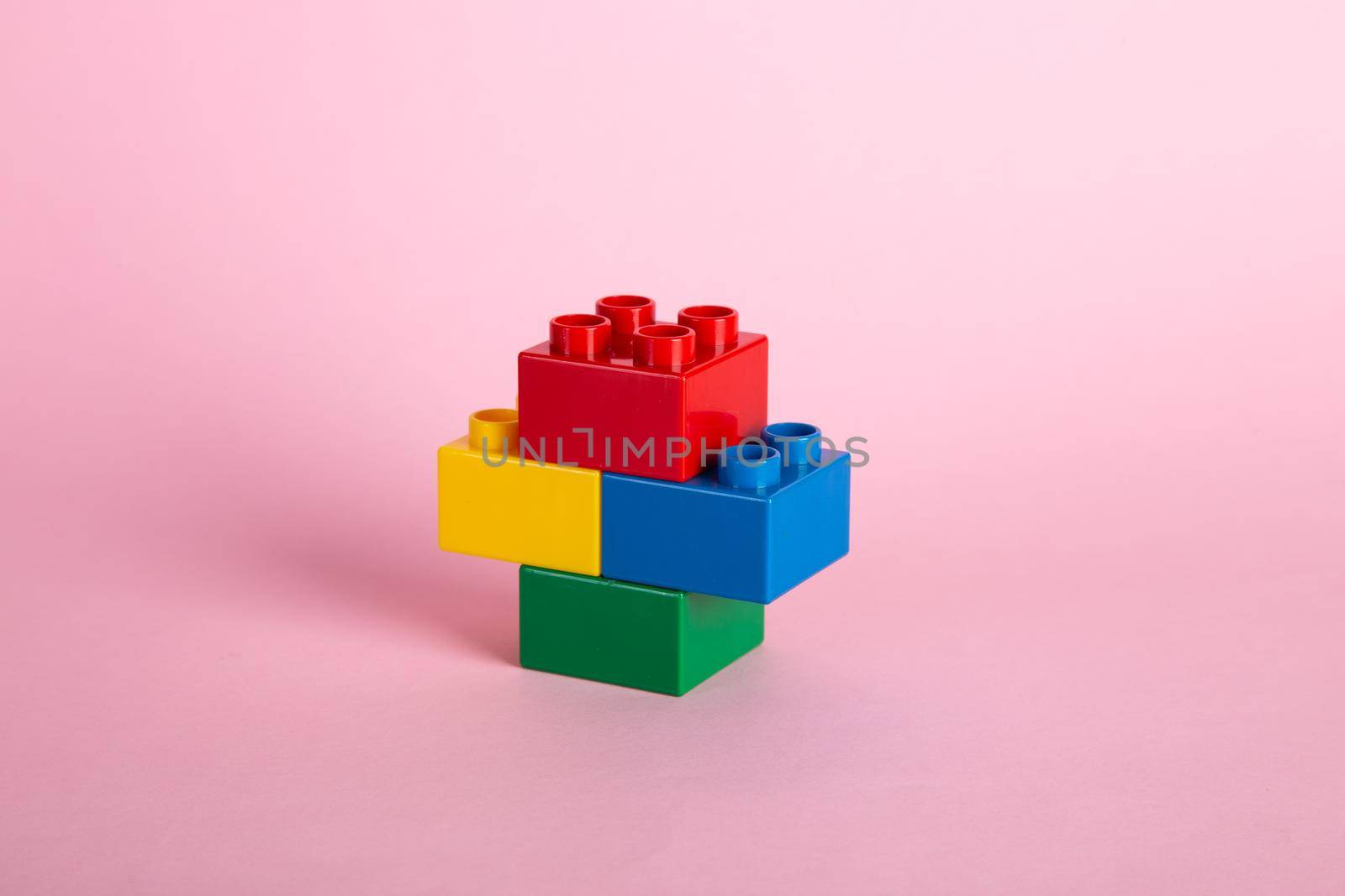 Plastic building blocks on pink background