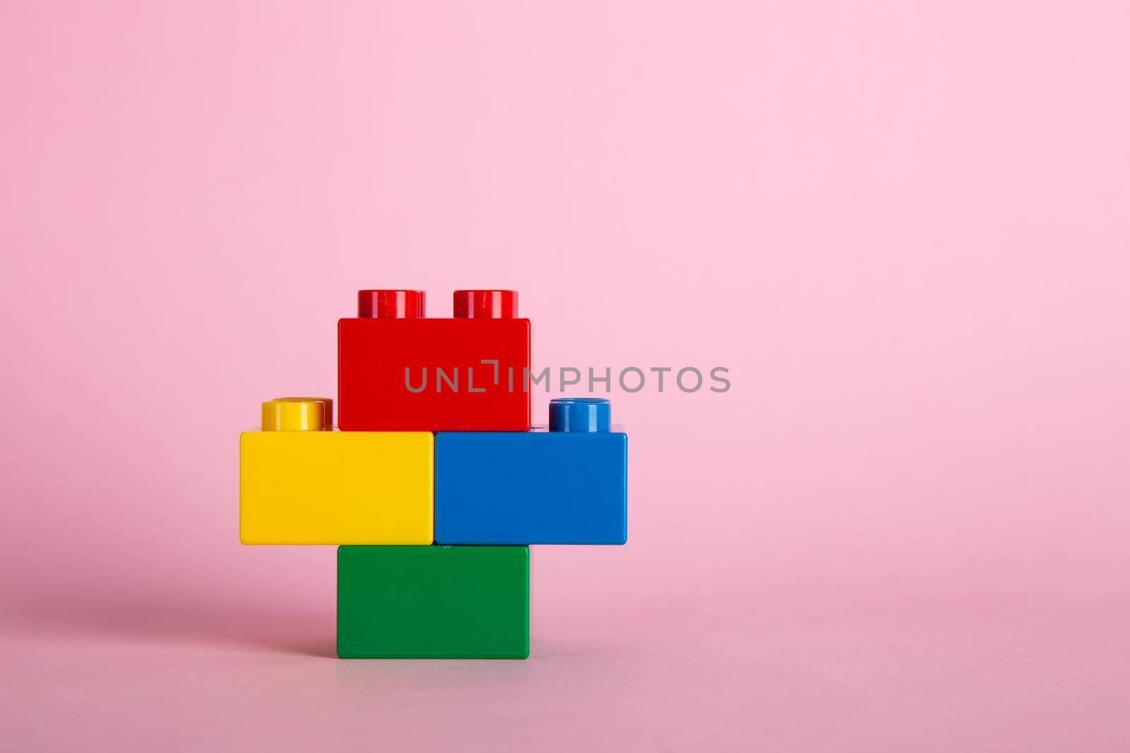 Plastic building blocks on pink background